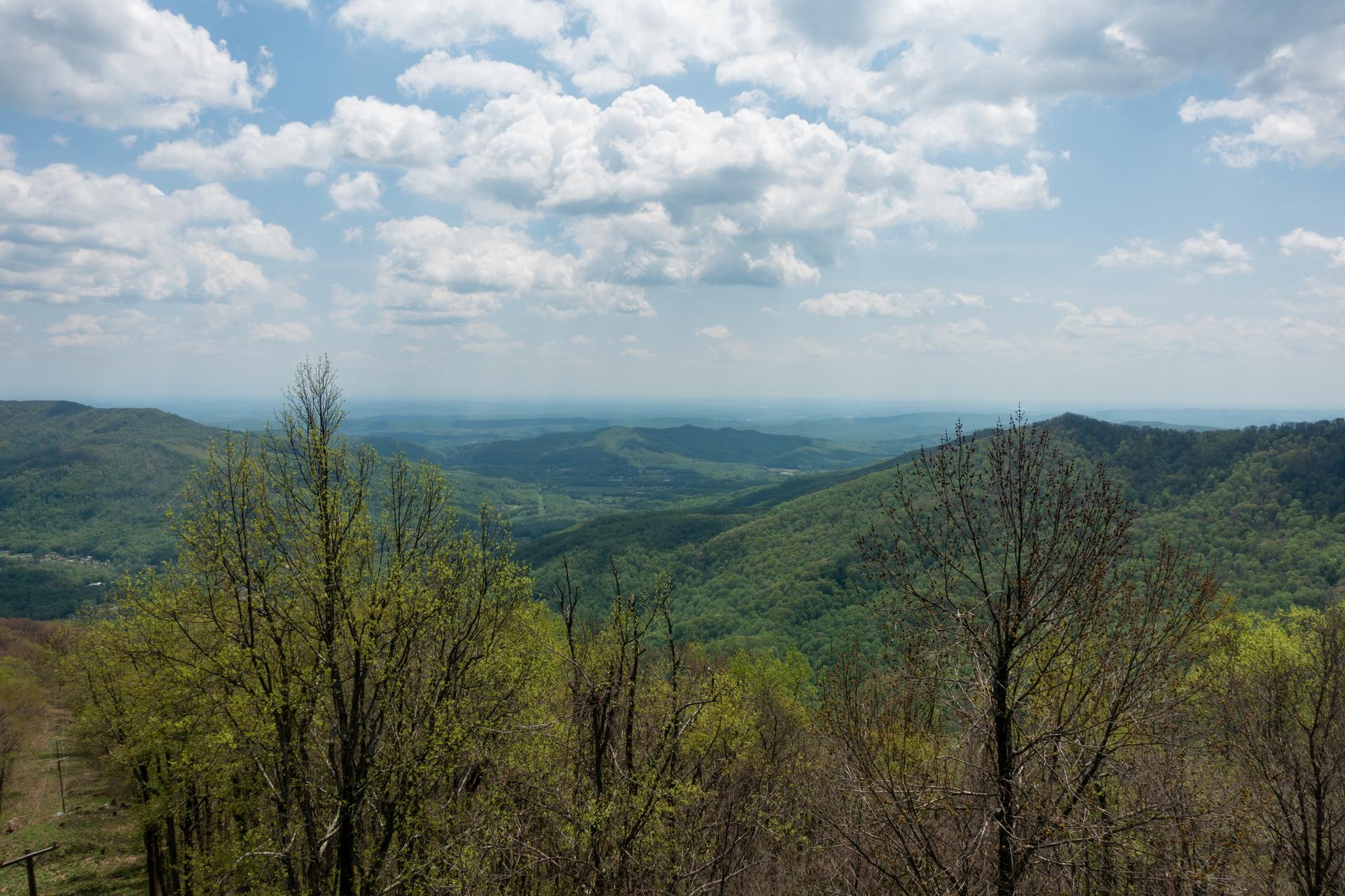 An expansive mountain landscape with green peaks under a cloudy sky.
