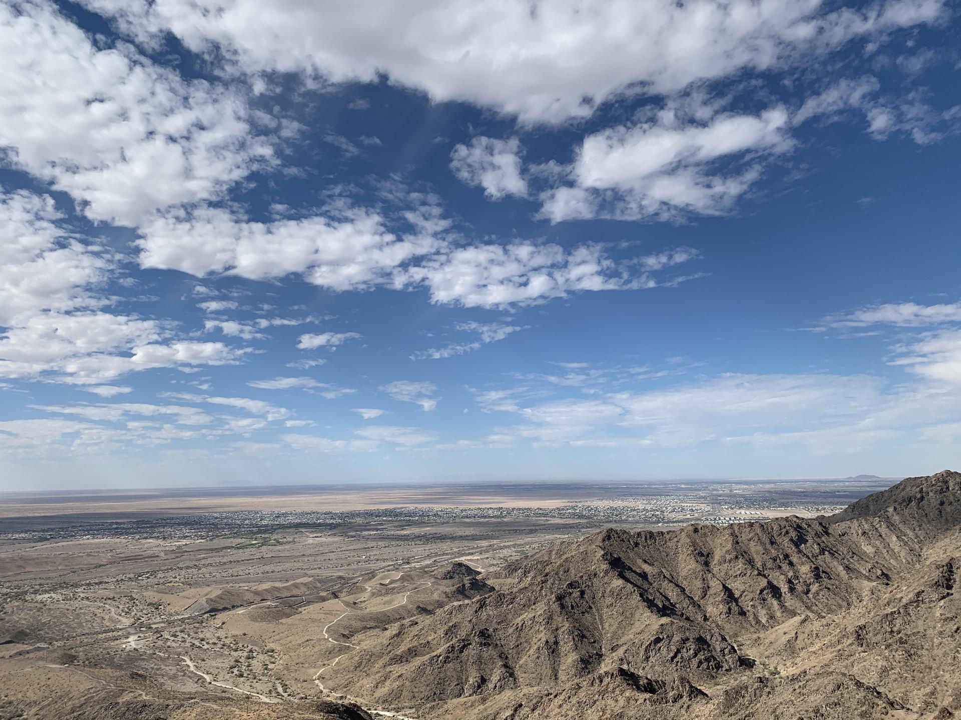 Expansive view of a vast desert valley from a rocky mountain peak.