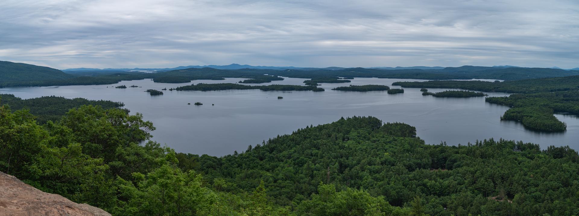 Panoramic view of a vast lake dotted with islands, surrounded by forests.