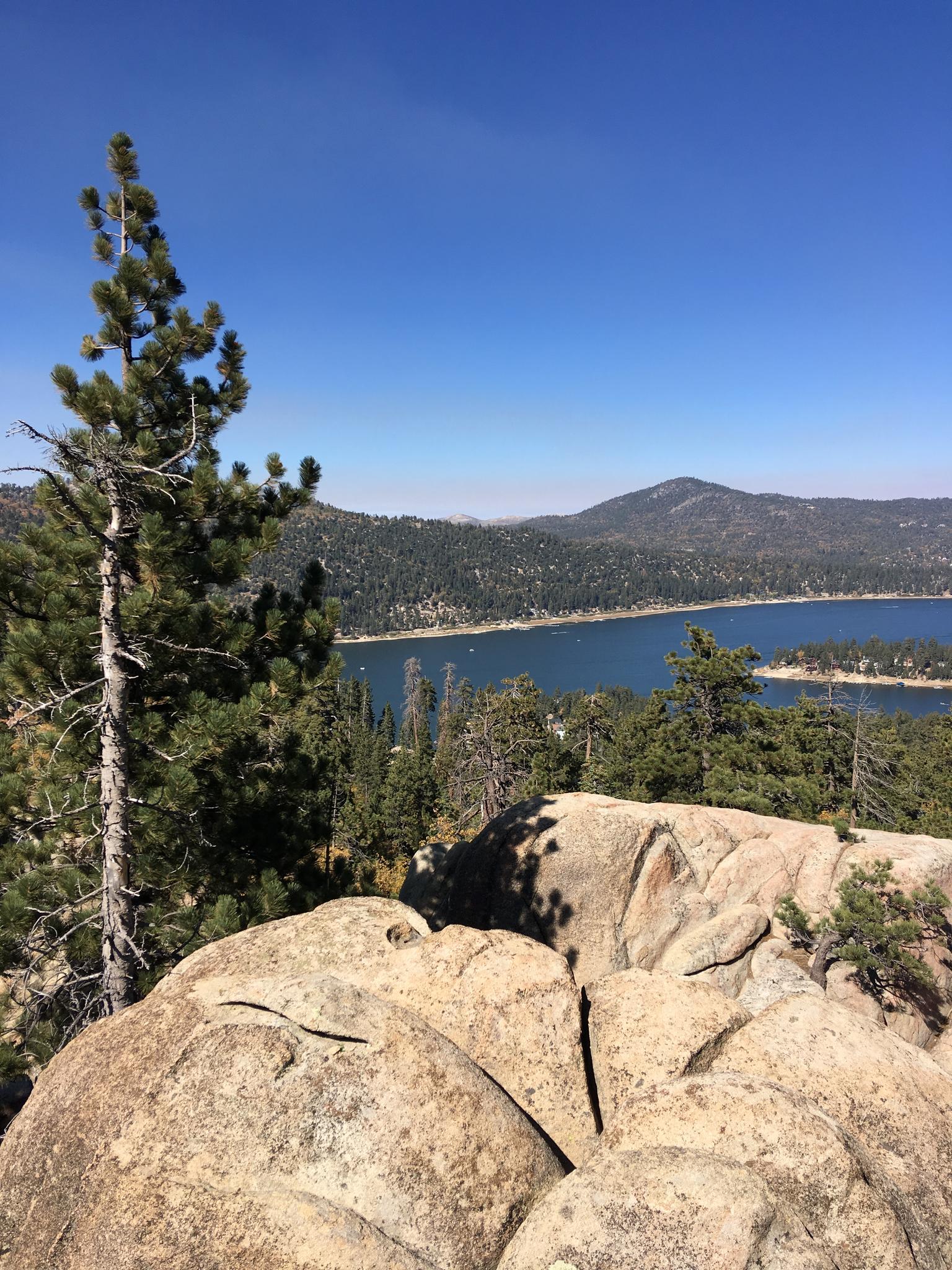 Panoramic view of a large lake and mountains from a rocky overlook.