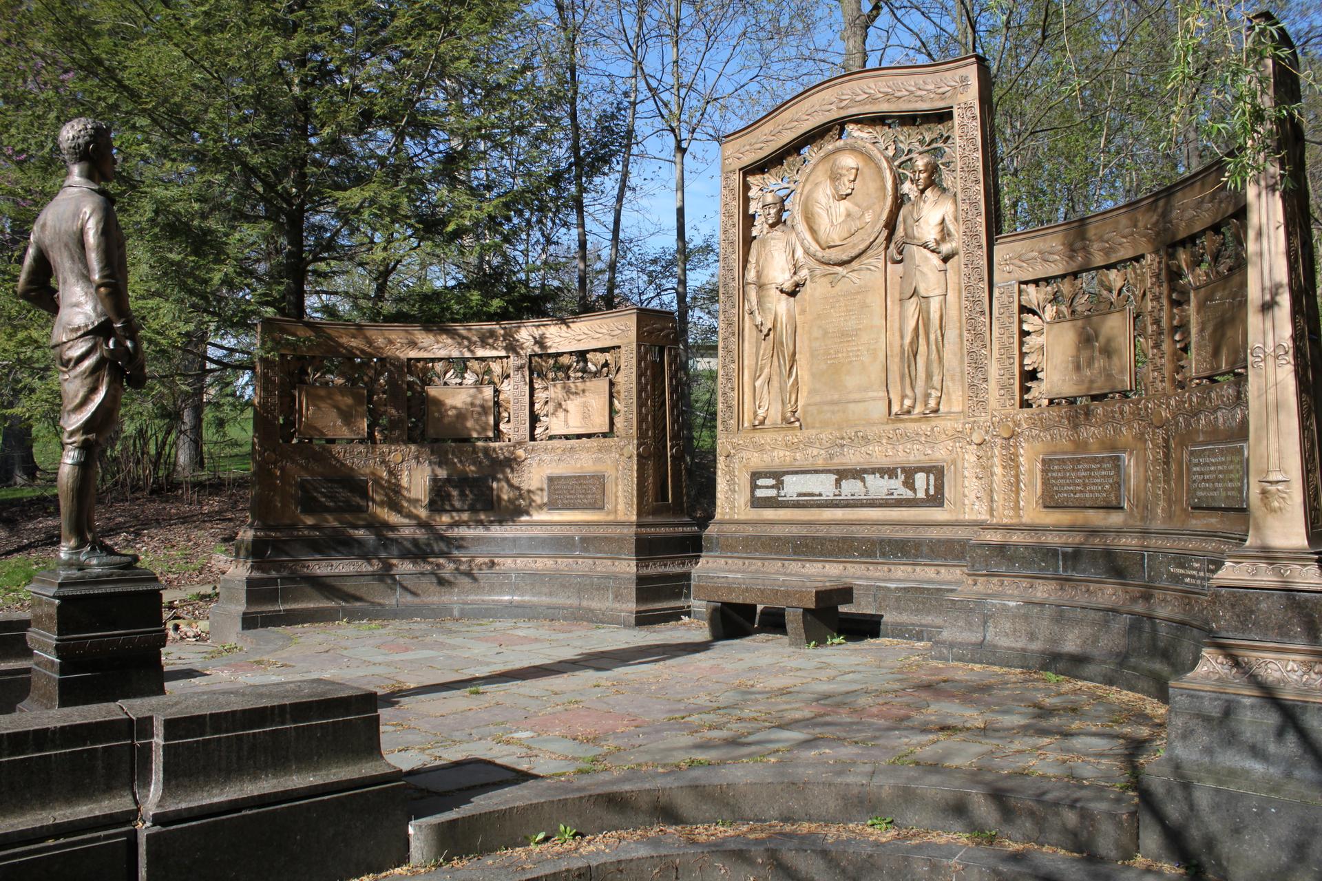 Ornate bronze statues and monuments in a sunny outdoor park setting.