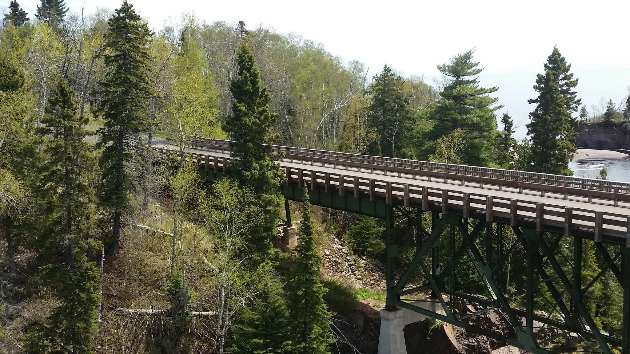 A long green bridge spans a forested valley on a bright day. - High Falls Trail - East