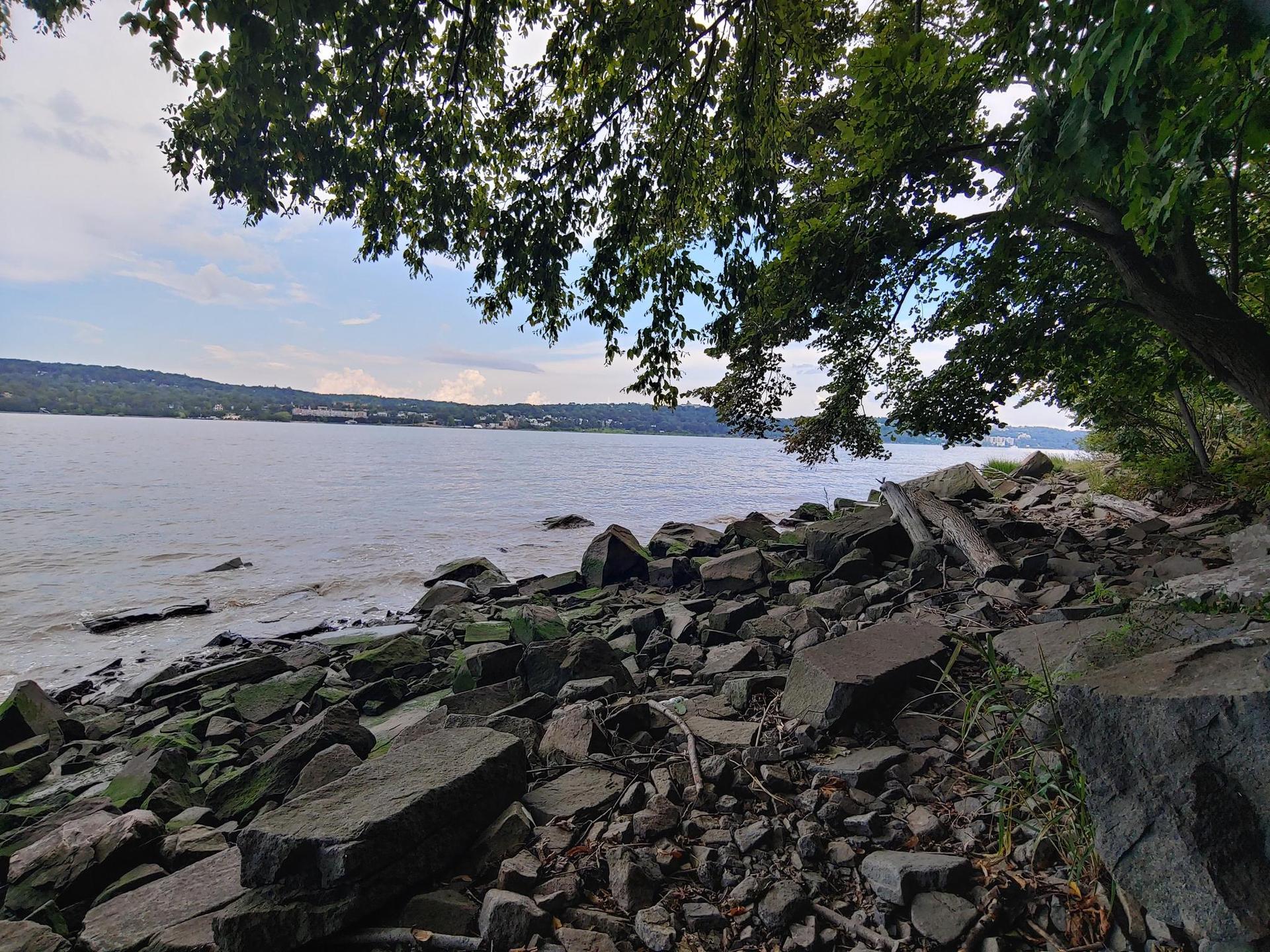 Rocky shoreline with a wide body of water under an overcast sky.