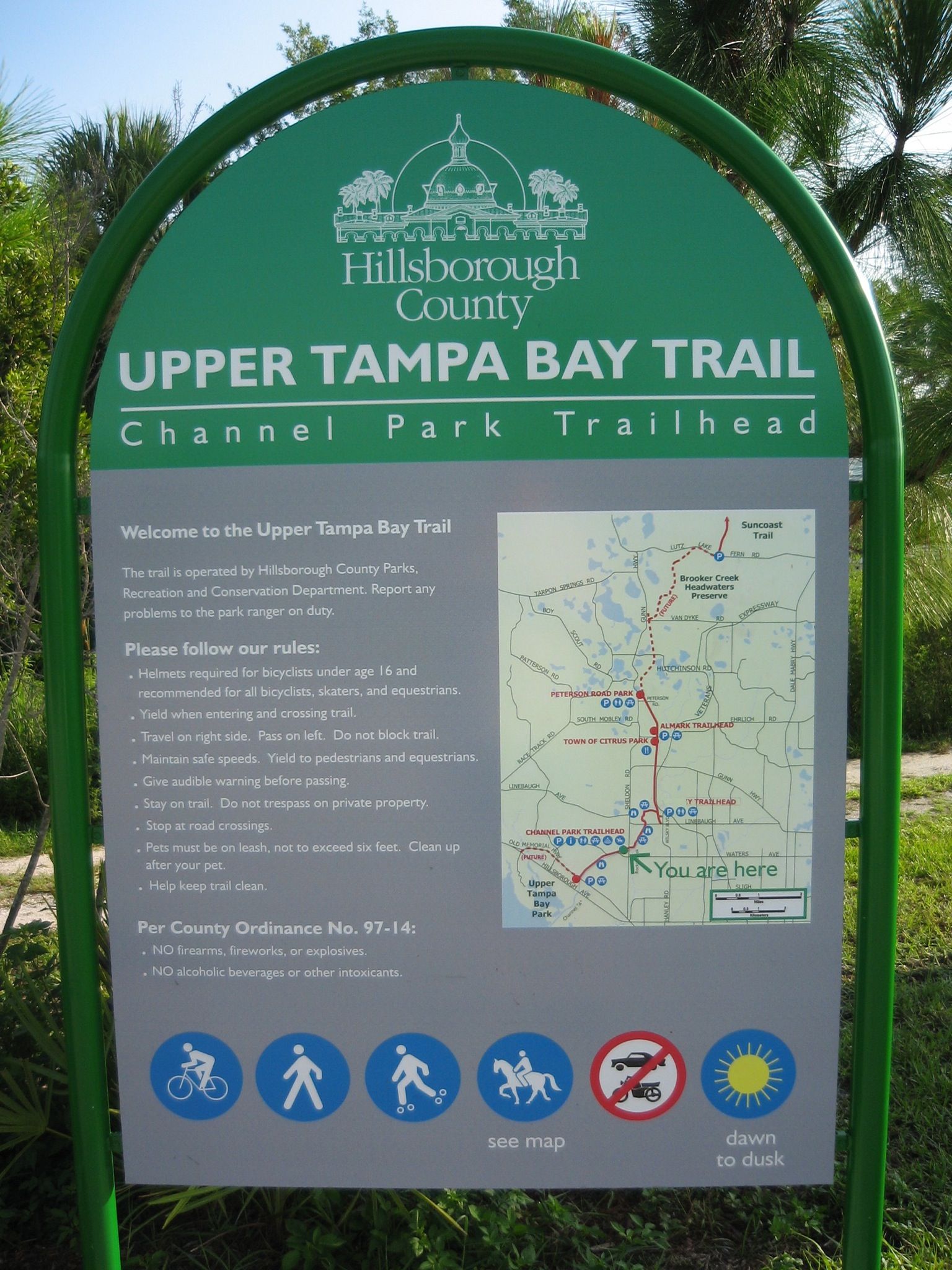 A green and gray trail information sign with a map and rules. - Upper Tampa Bay Trail
