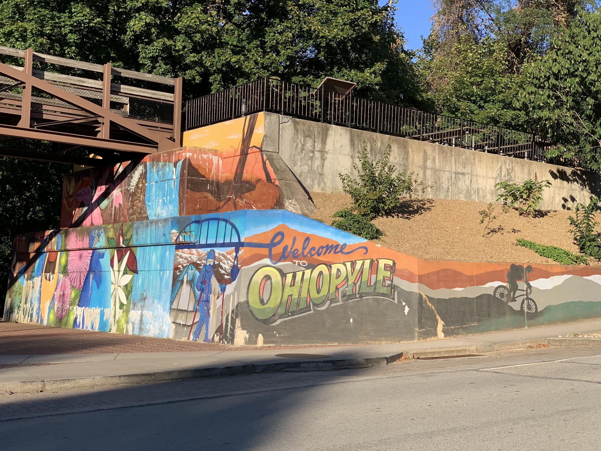 A colorful mural on a concrete wall depicts people and a cyclist.