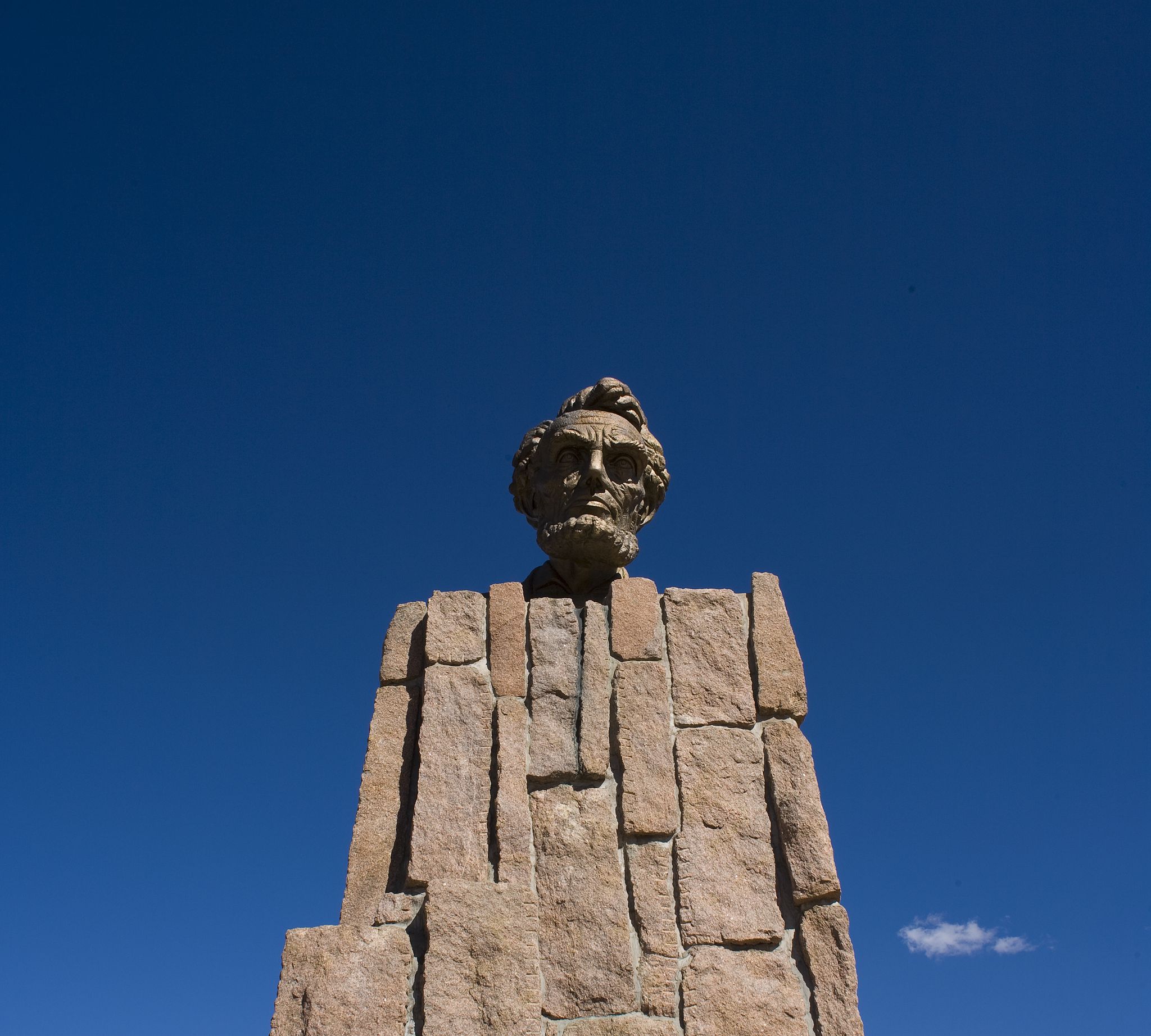 Stone bust of a man on a pedestal against a clear blue sky. - Laramie to Cheyenne century ride