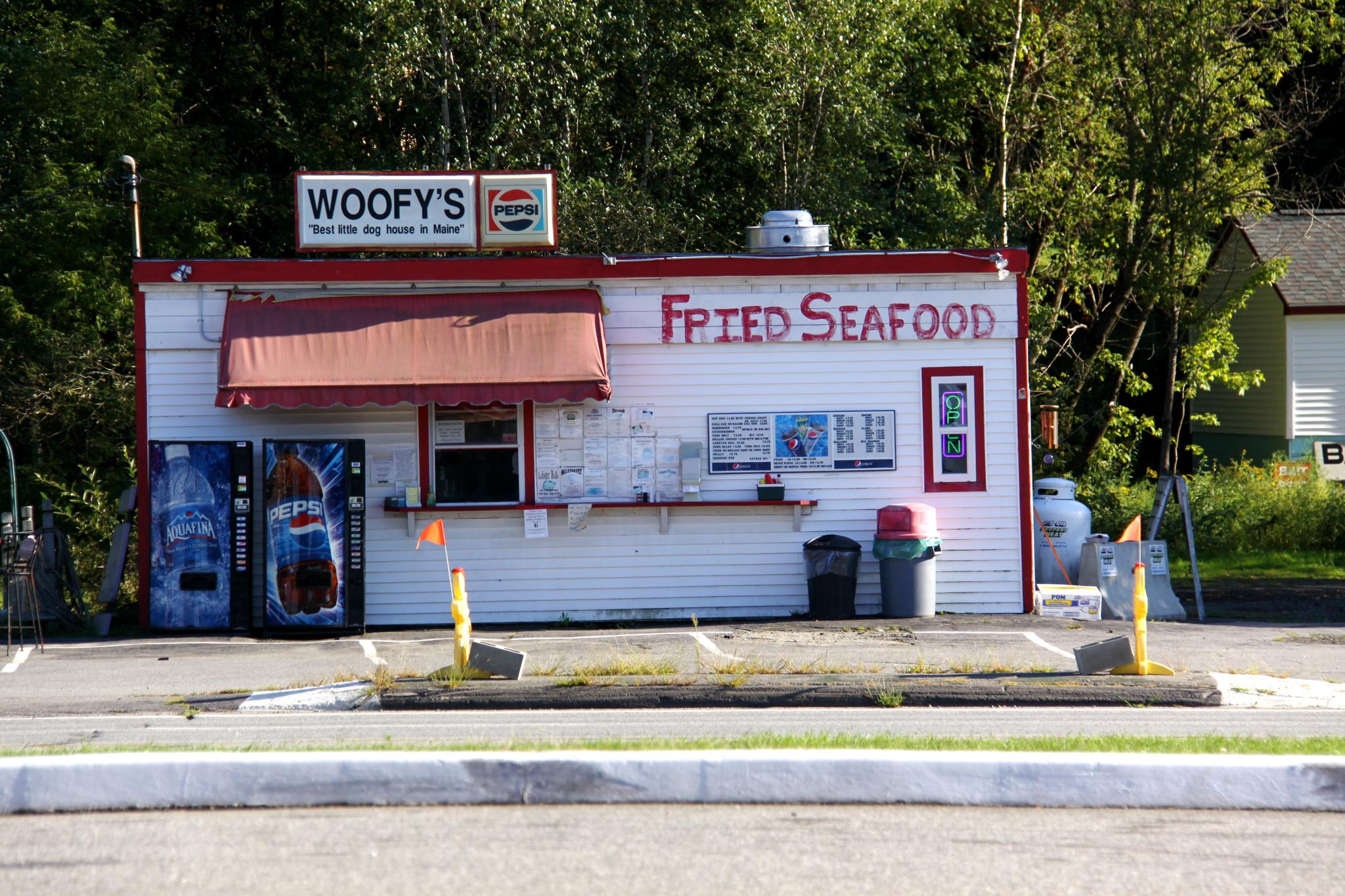 Small white "Fried Seafood" stand with red trim in daylight.