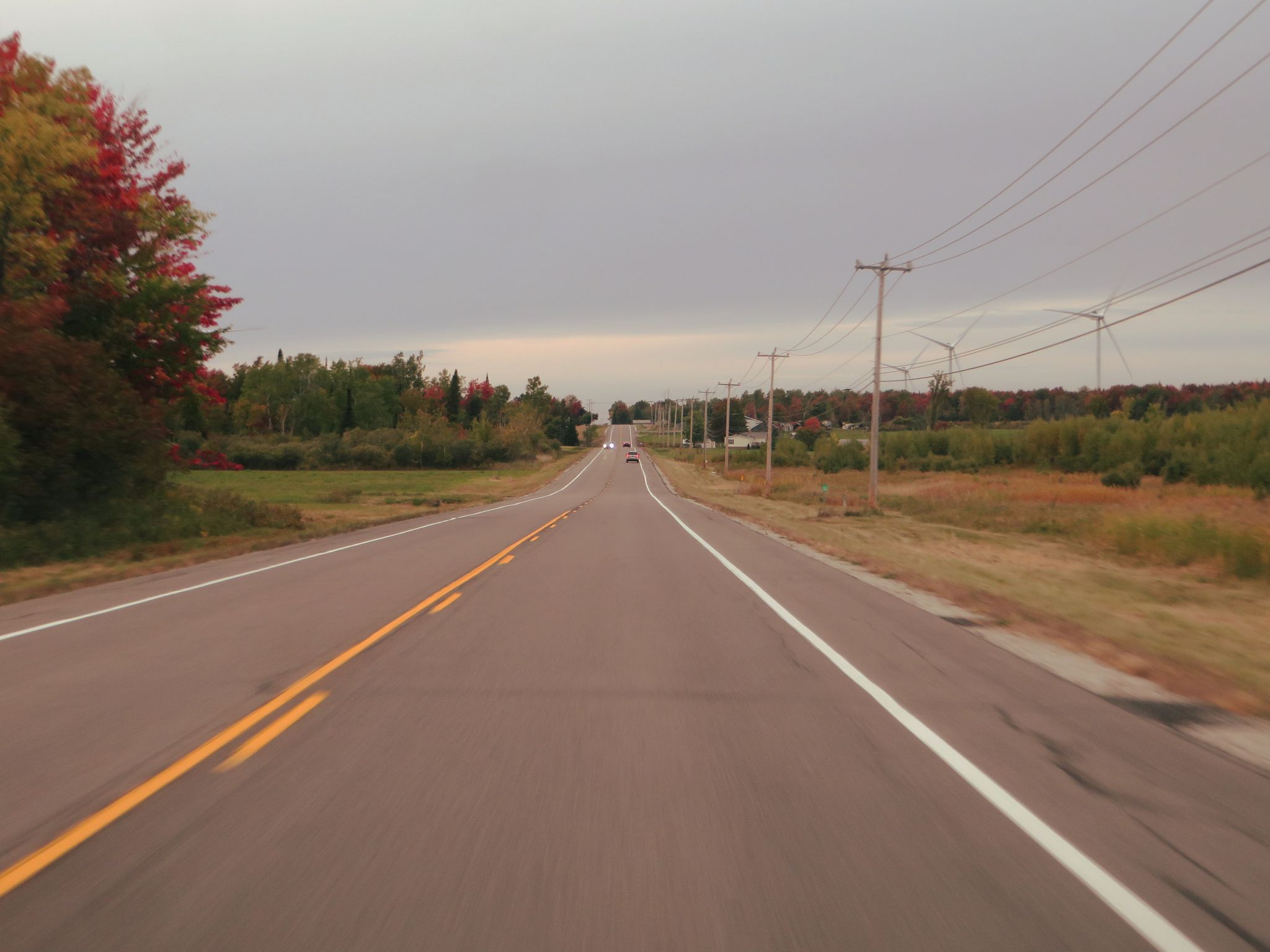 Long, empty rural road under an overcast sky with power lines. - Chateaugay to Plattsburgh via NY Bike Route 11