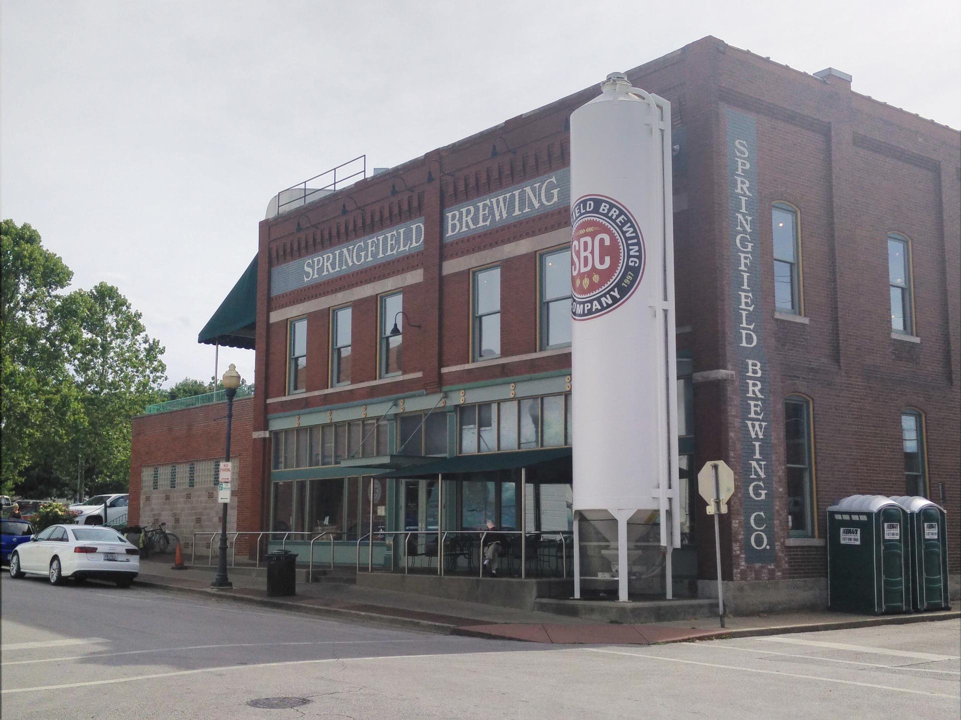 A large brick building with a white silo on a street corner.