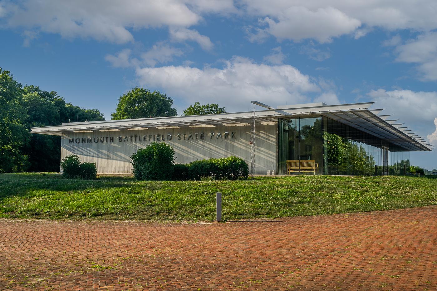 Modern building with glass and concrete on a grassy hill under a sunny sky.