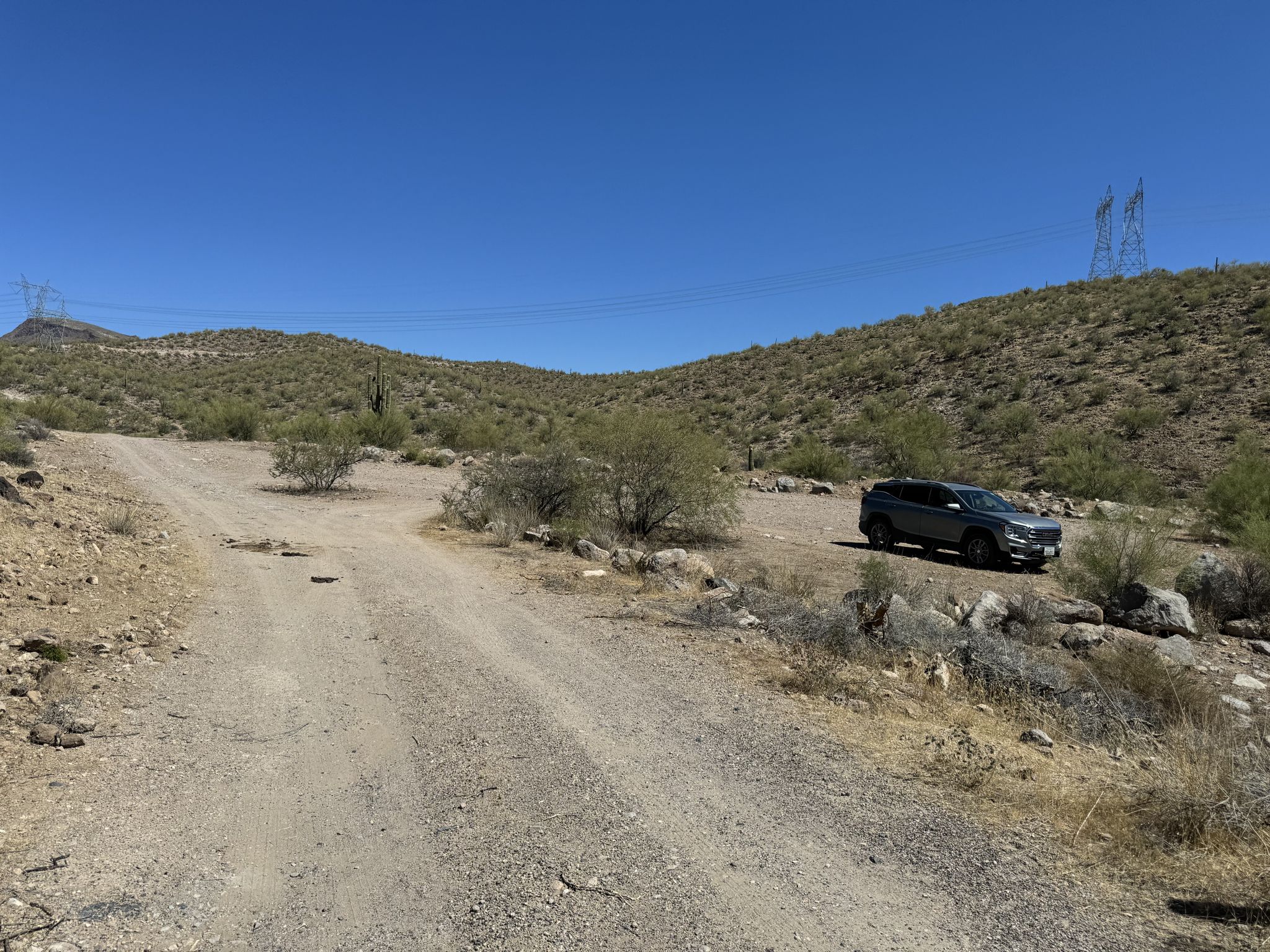 A gray car parked on a dirt road in a sunny, arid landscape. - Kaiser Hot Springs Trail