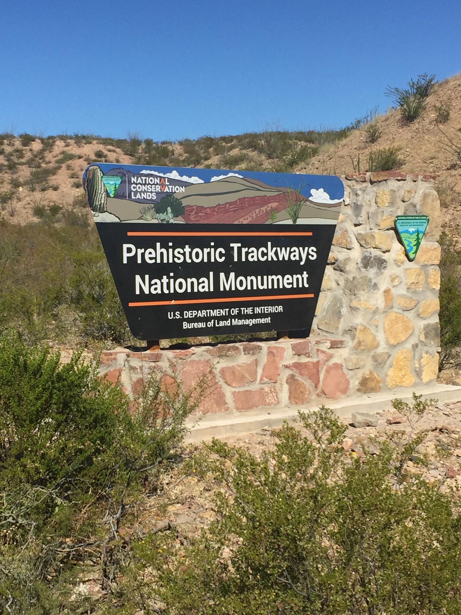 A large monument sign on a stone base under a bright blue sky.