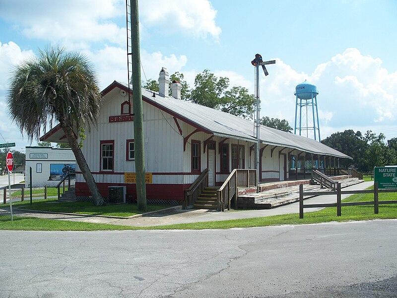 An old white and red building with a palm tree and water tower.