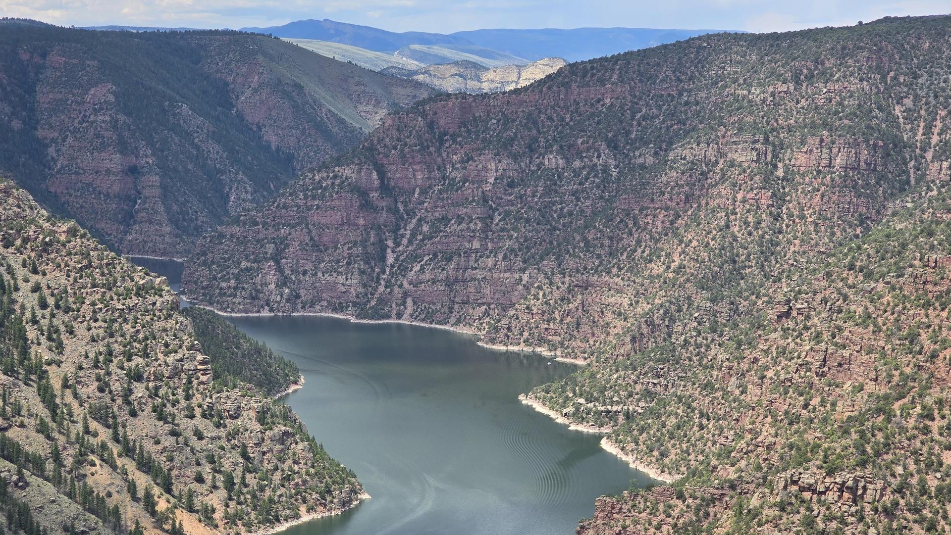 A wide river flows through a deep, rocky canyon with forested slopes.