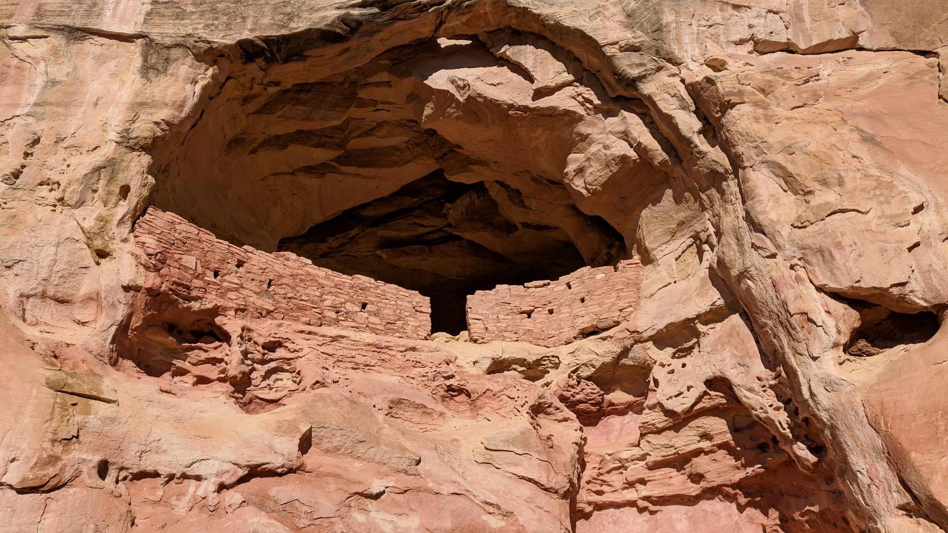 Ancient stone dwelling built into a large, dark rock overhang.