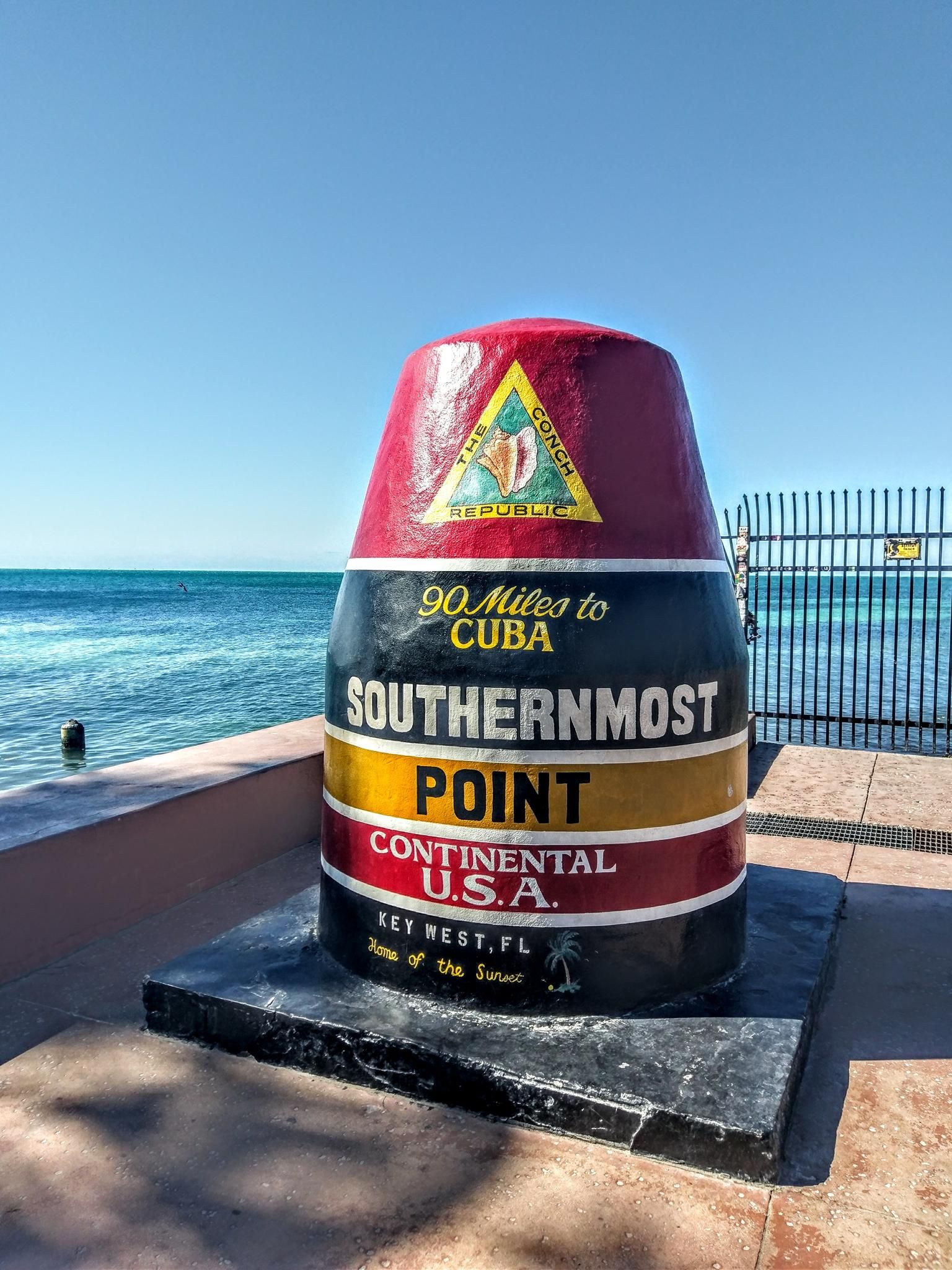 Colorful monument by the ocean under a bright blue sky. - Key West Cycling Loop