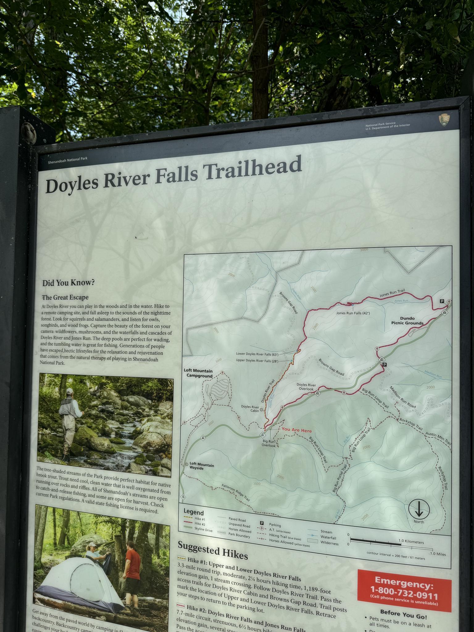 Close-up of a trailhead information sign with maps and descriptive text.