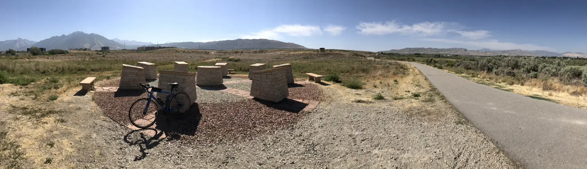 Bicycle parked at a stone monument on a sunny, dry path.