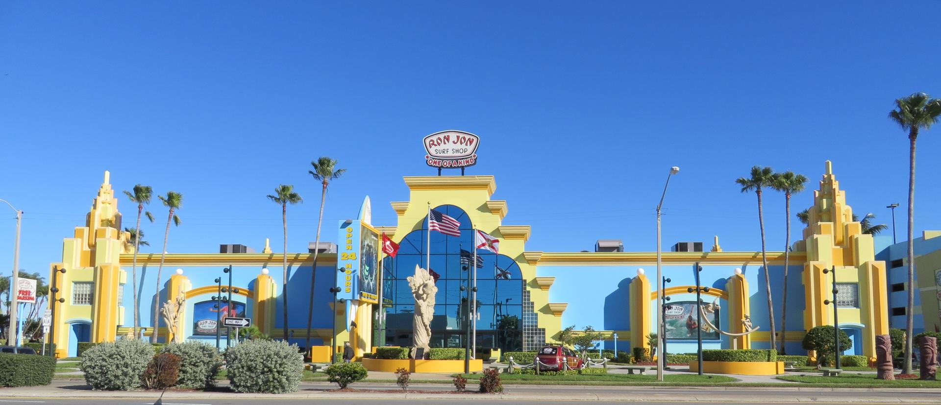 Brightly colored building under clear blue sky with palm trees.
