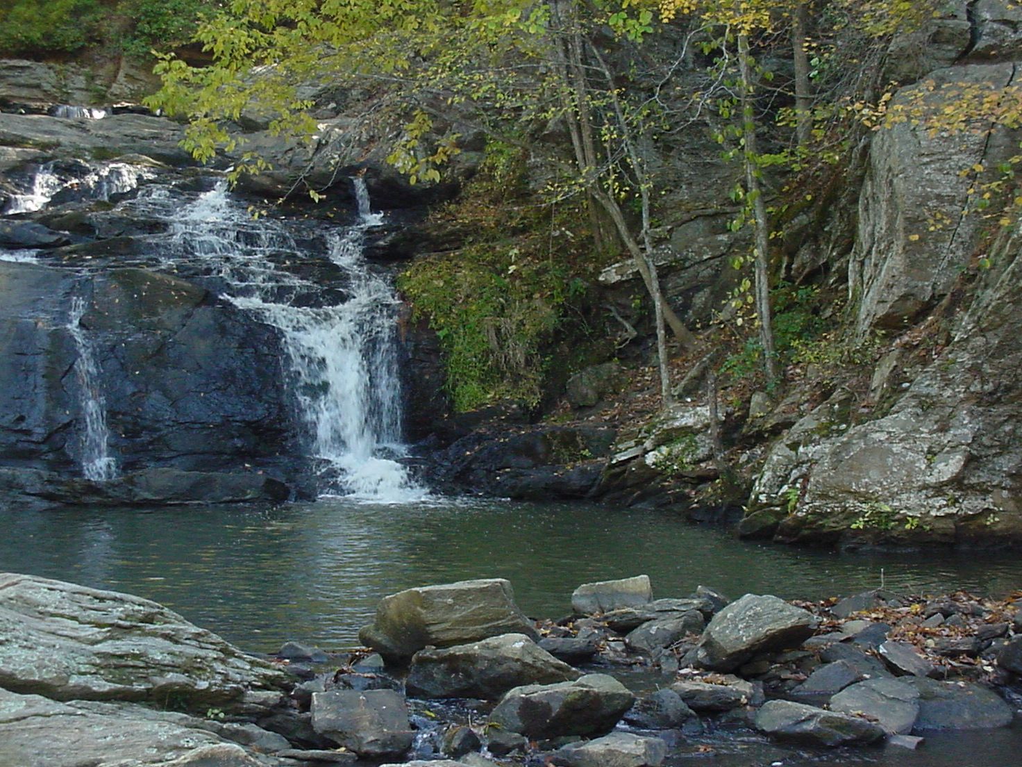 Waterfall cascades over rocks into a dark pool surrounded by trees and boulders. - Cochran Mill Park – Upper Wooten Gravel Trail loop from S.E. Fairburn