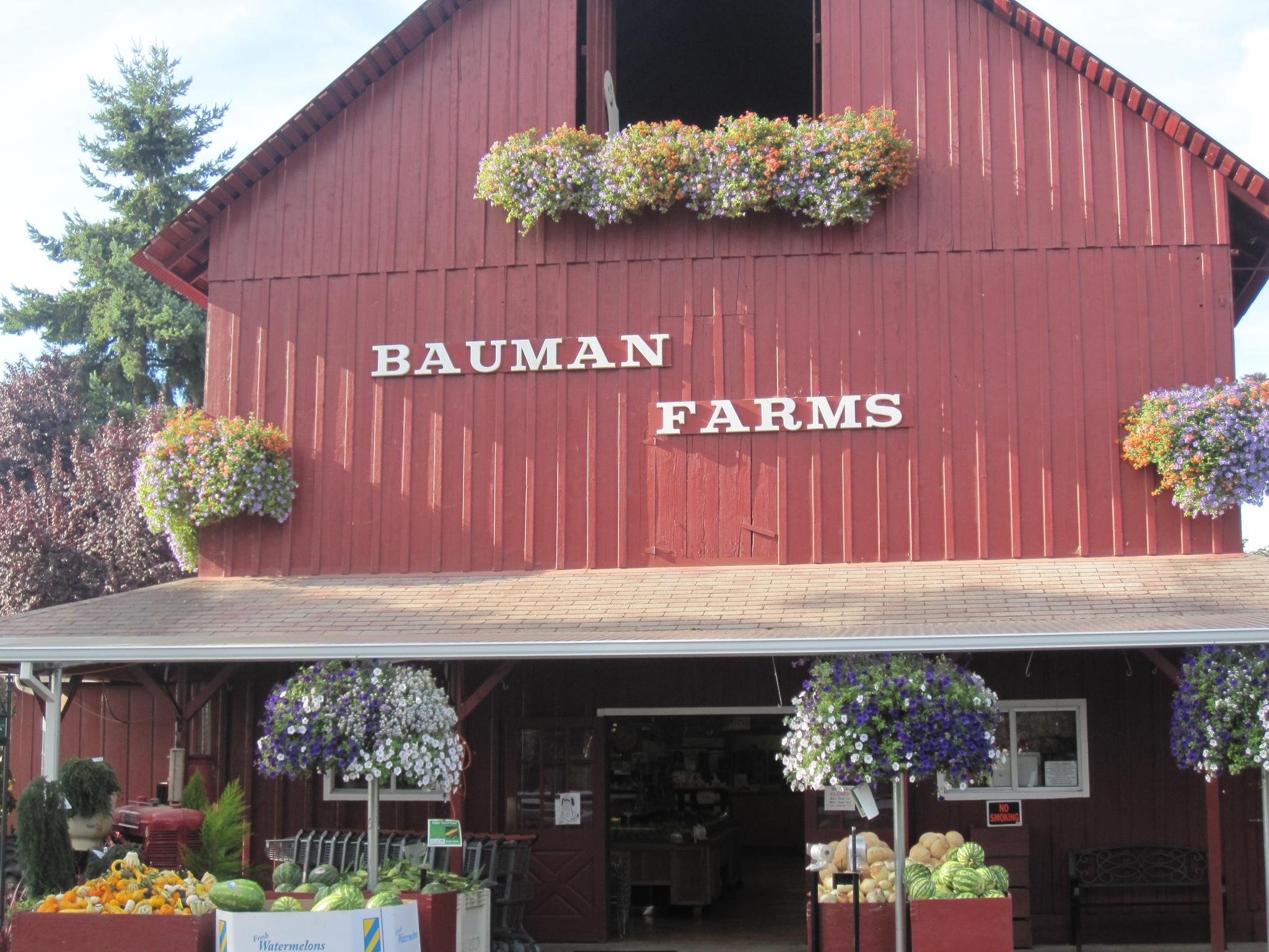 Red barn-like building entrance adorned with many hanging flower baskets.