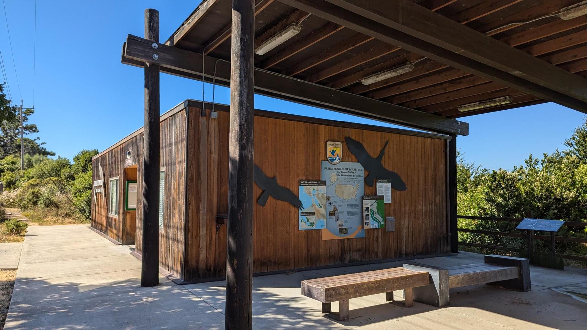 A wooden building with informational panels under a covered outdoor area.