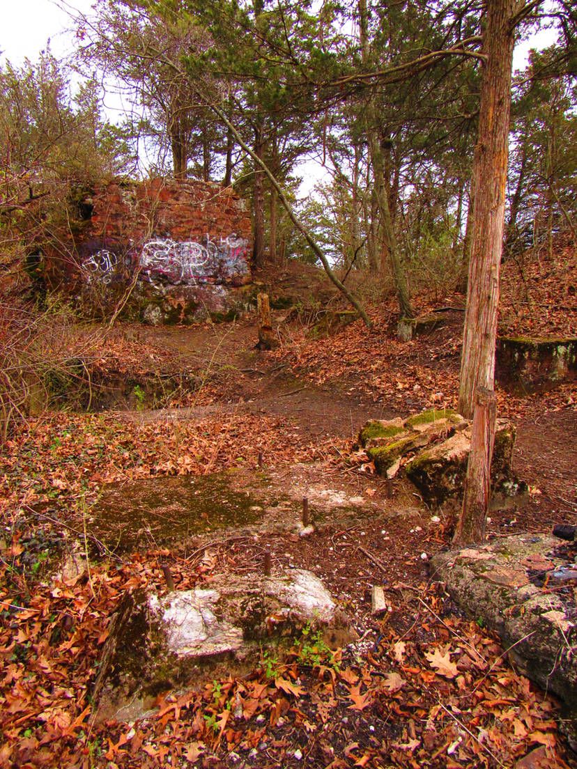 Overgrown forest with brick ruins covered in graffiti under an overcast sky. - The Branford Trail