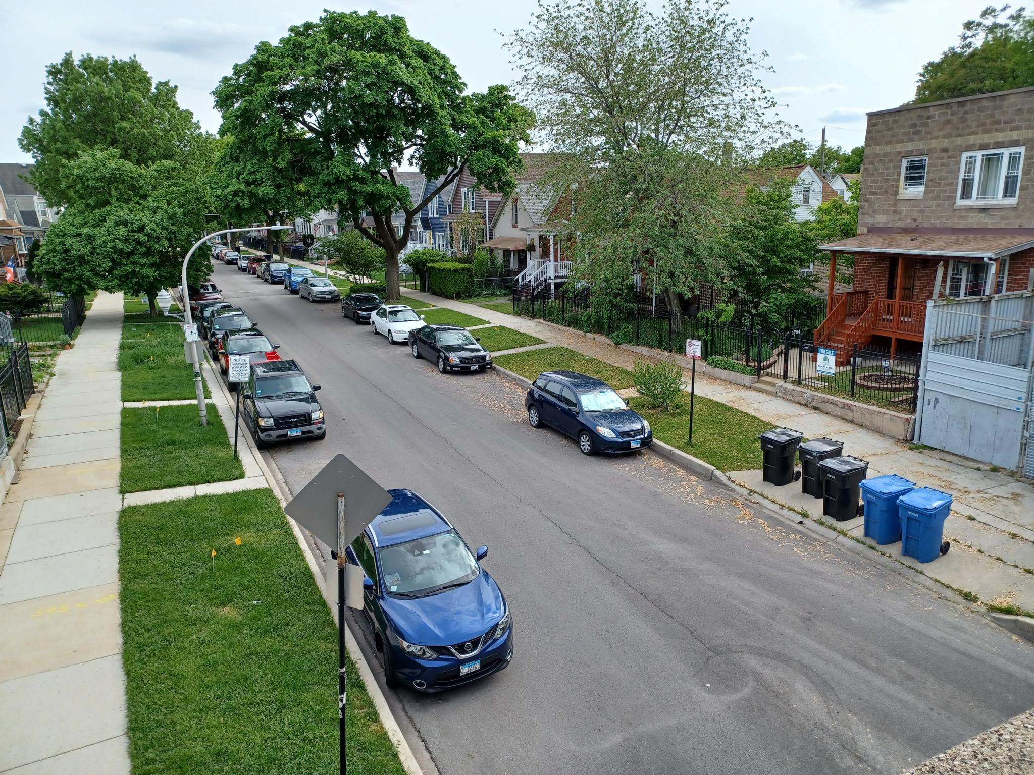 An overhead view of a residential street with parked cars and houses.
