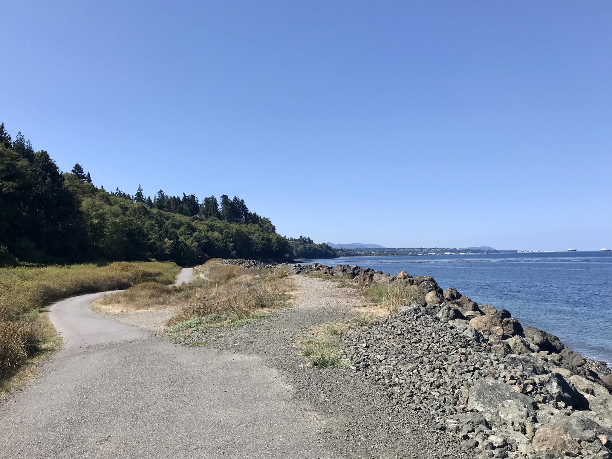 Paved path next to a rocky shore and calm water on a clear day. - Olympic Discovery Trail: Port Angeles Waterfront