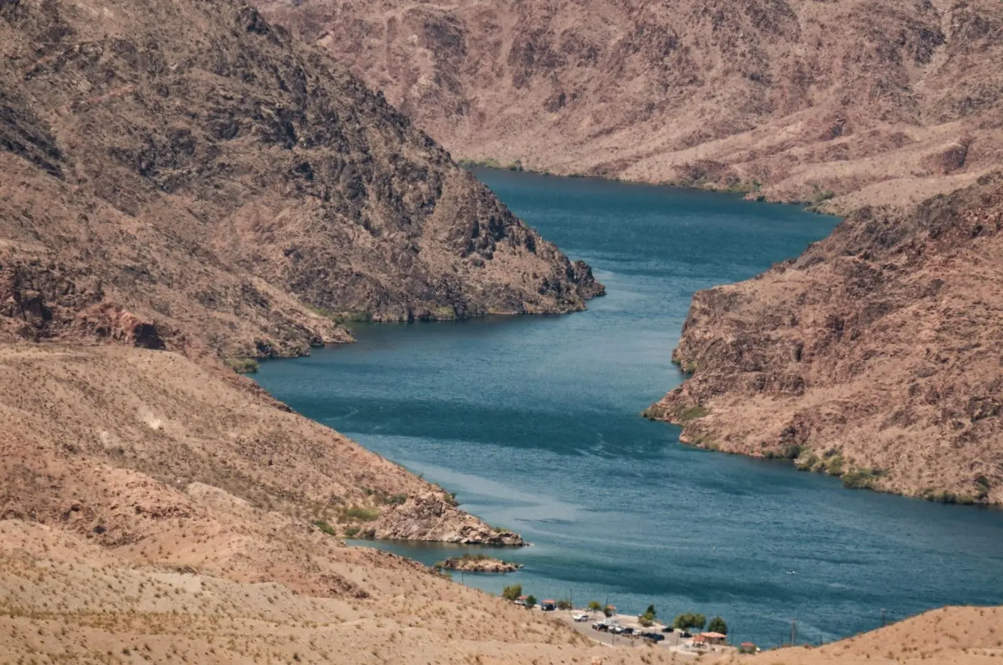 Turquoise river winding through arid, rocky canyons under bright light.
