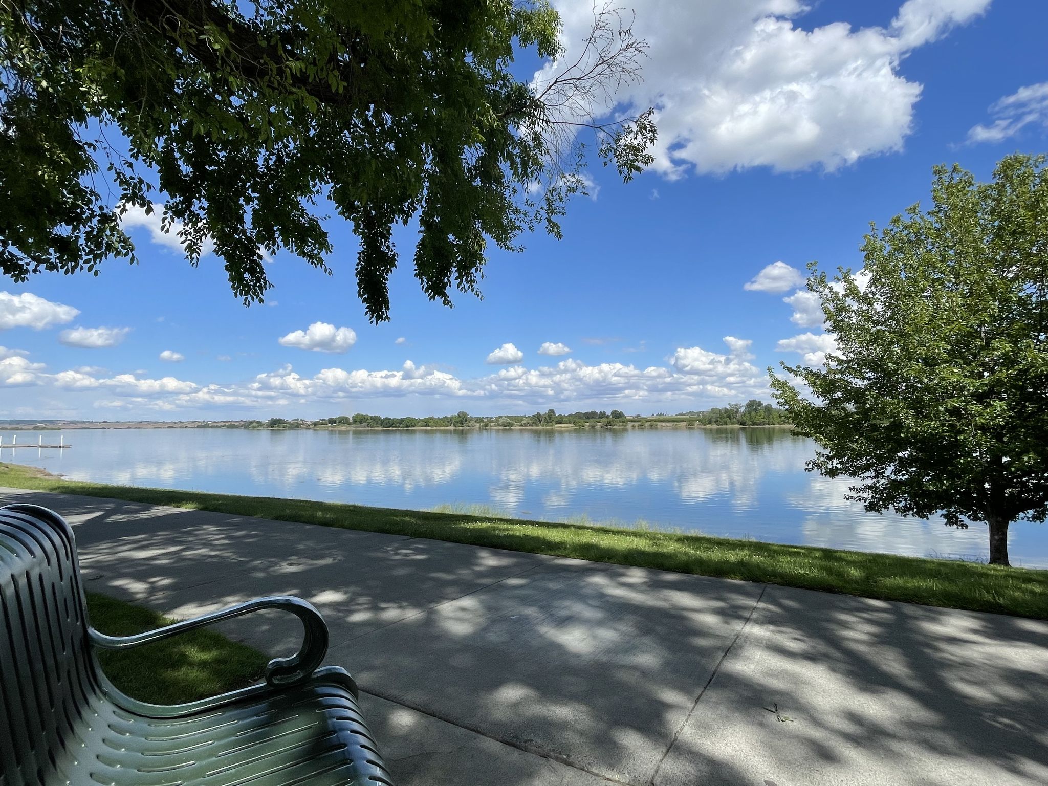Park bench overlooking a wide lake under a bright, cloudy sky. - Riverfront Trail – Columbia Point Marina Park loop from Columbia Point South