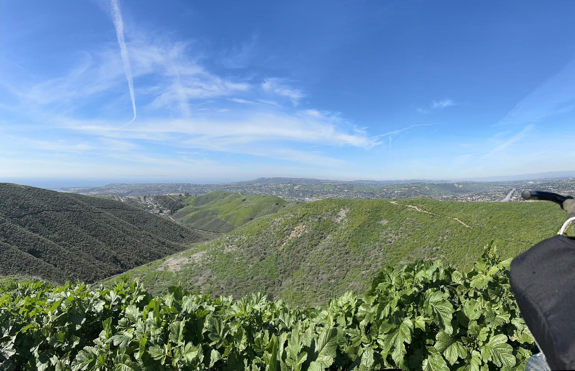 Vast green valleys and distant hills under a bright blue sky.
