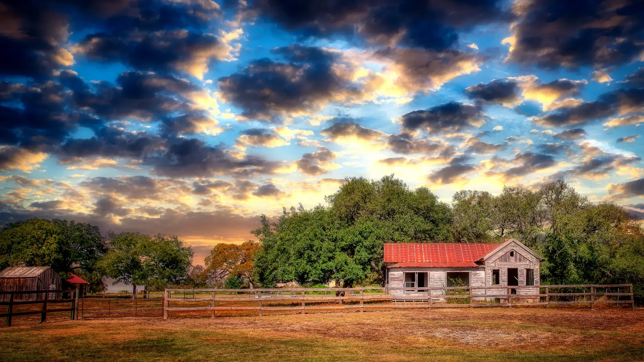 Weathered house with red roof under a dramatic, colorful cloudy sky. - Berry Springs Park Prairie Trail
