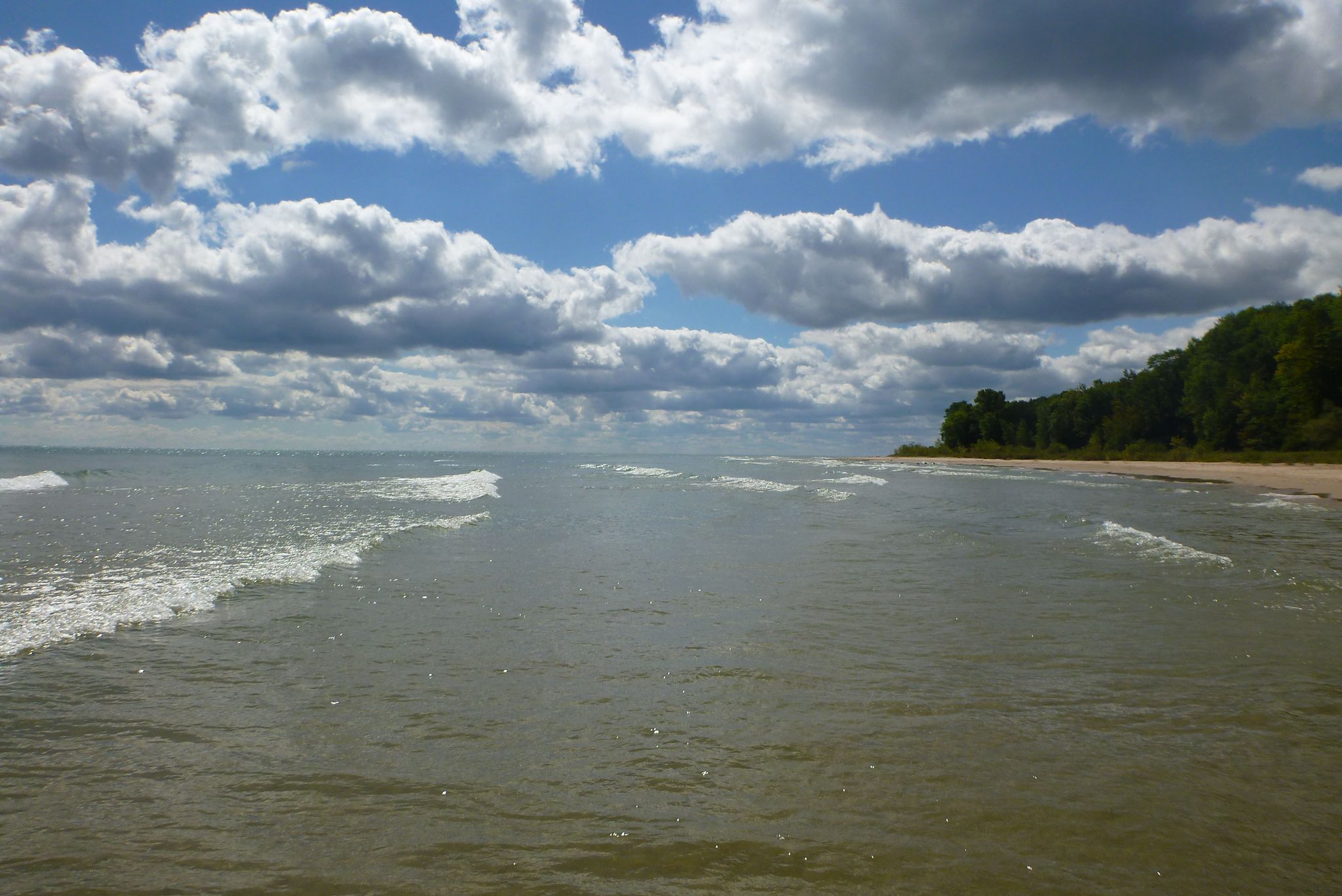 Wide body of water with small waves, sandy beach, and cloudy sky. - Harrington Beach – Quarry Lake loop from Harrington Beach State Park