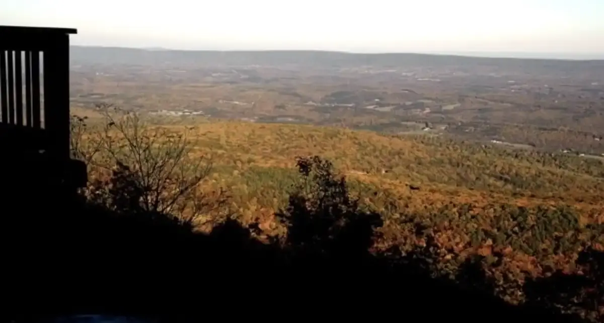 Expansive valley view with autumn trees under a bright sky.
