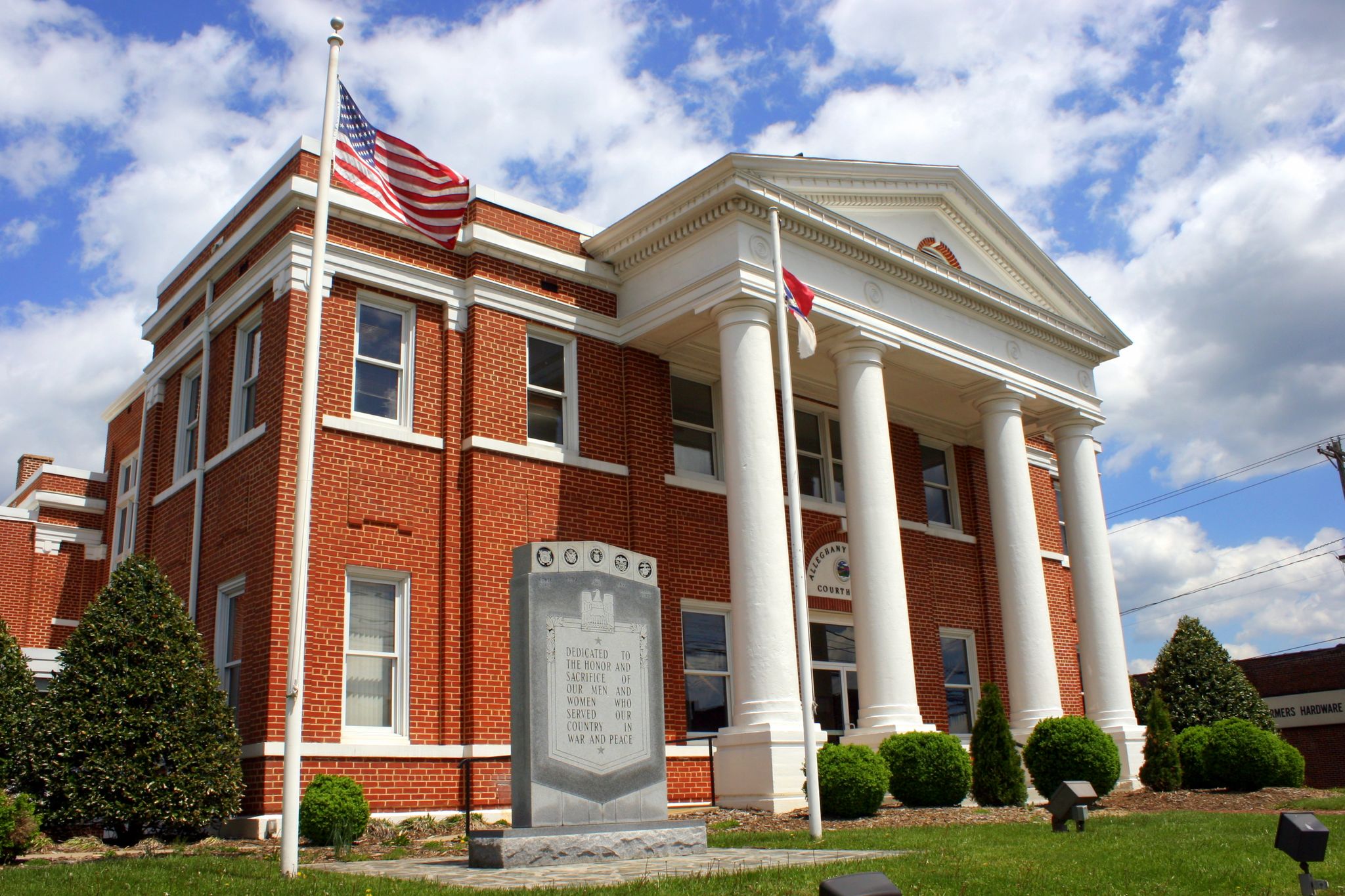 Large brick building with white columns, flags, and a monument under a cloudy sky. - Sparta and North Line Trace Loop