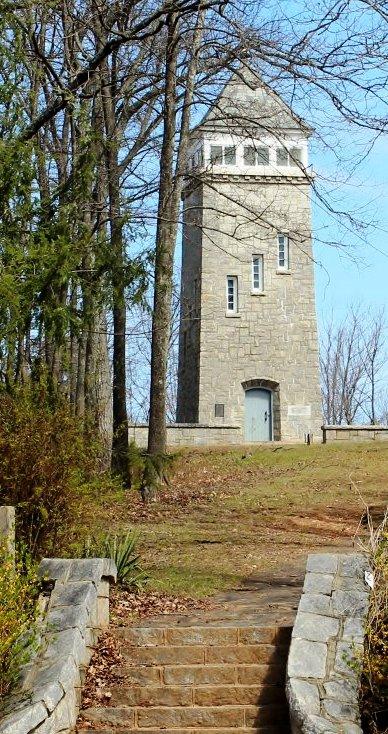 Tall stone tower on a hill, surrounded by bare trees and stone steps.