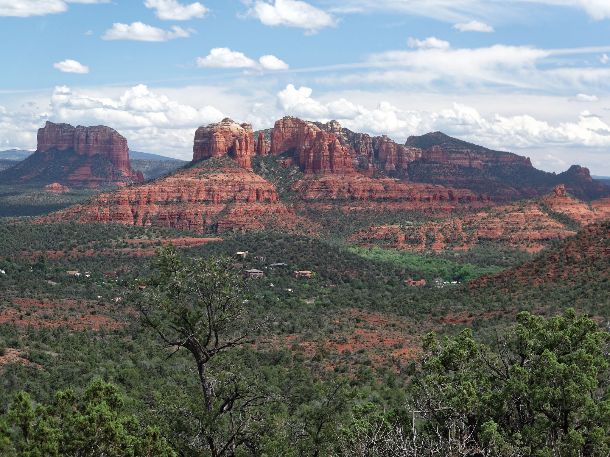 Panoramic view of majestic red rock mountains and green desert landscape under a cloudy sky. - Red Rock Loop