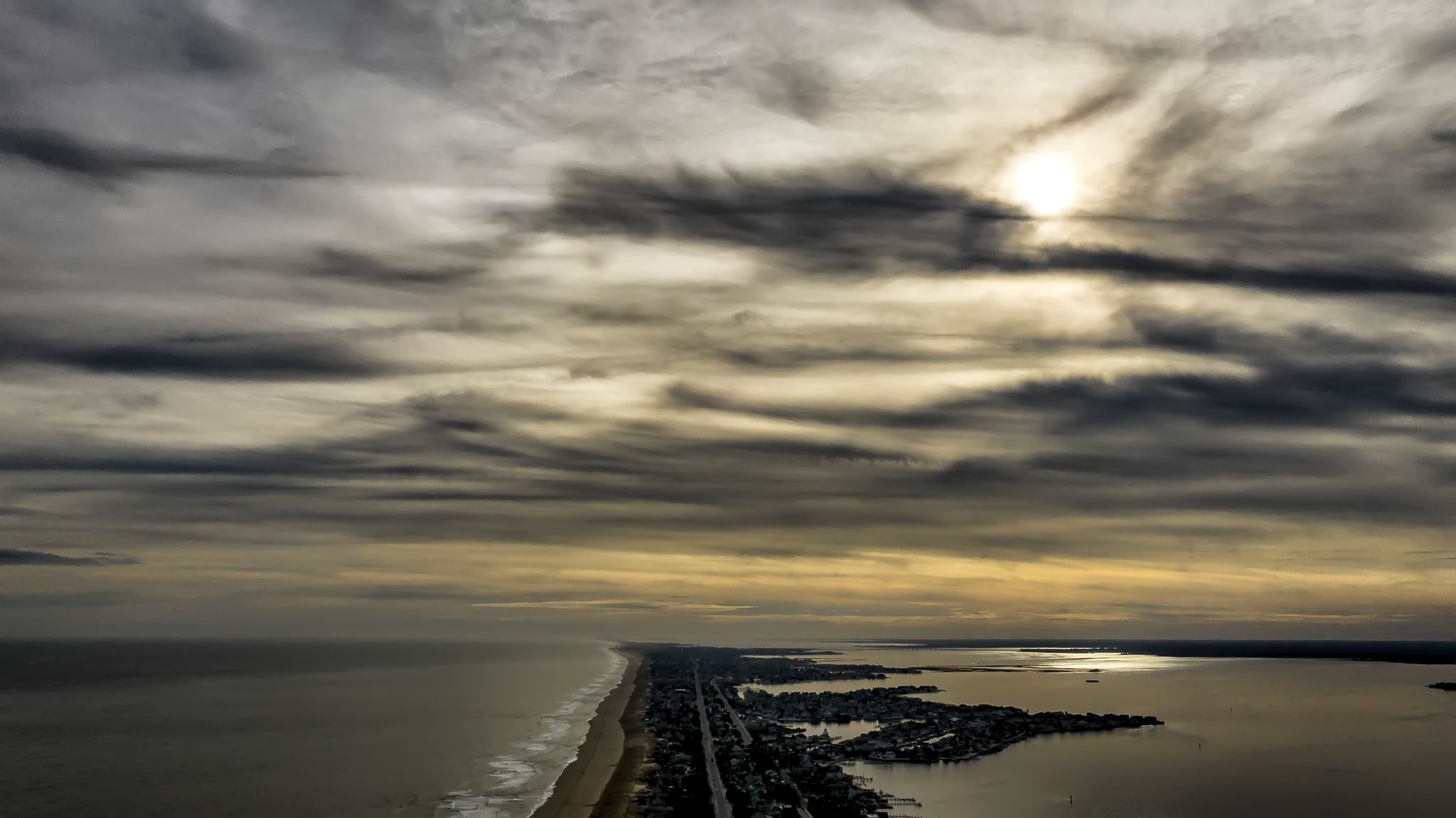 Aerial view of a coastal strip between ocean and bay under dramatic cloudy sky. - Cattus Island Main Trail and Hidden Beach Trail Loop