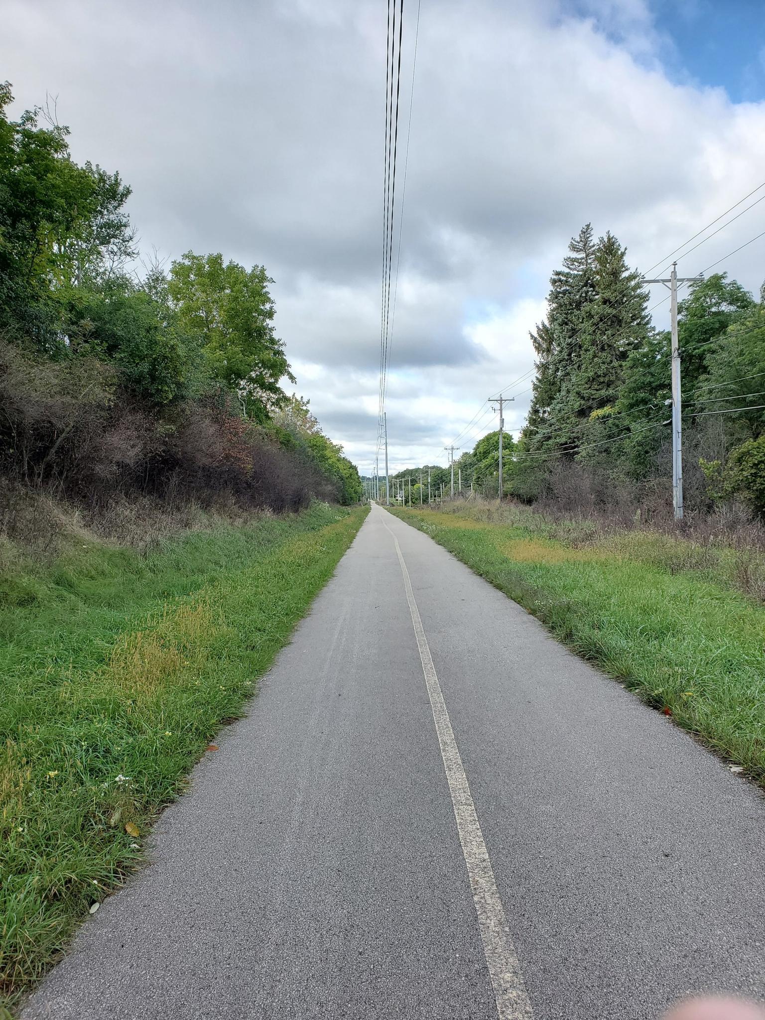 Long paved path stretching into the distance under a cloudy sky.
