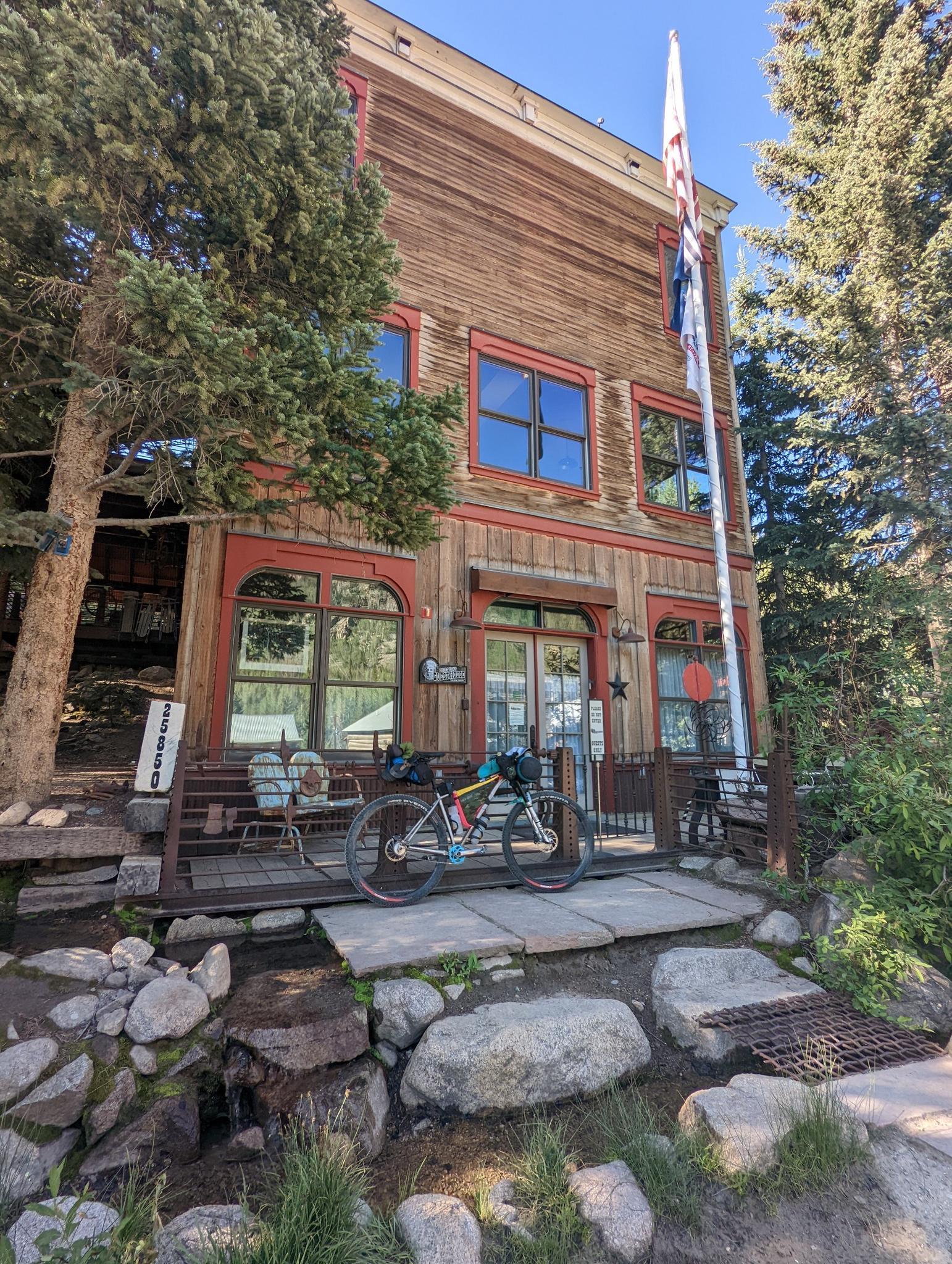 A rustic wooden building with a bicycle parked outside, flag flying.