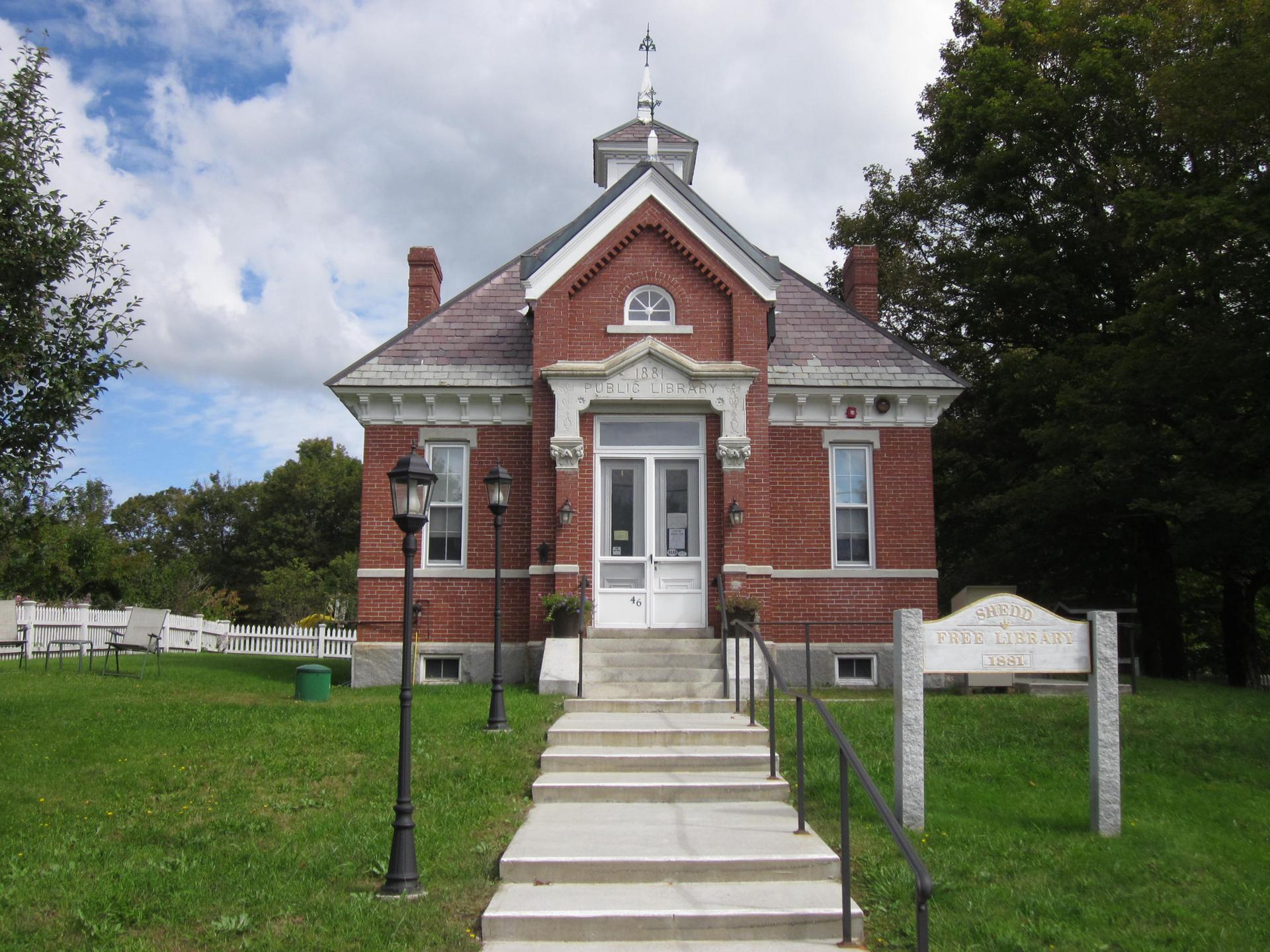 Red brick building with white trim and cupola under a cloudy sky.