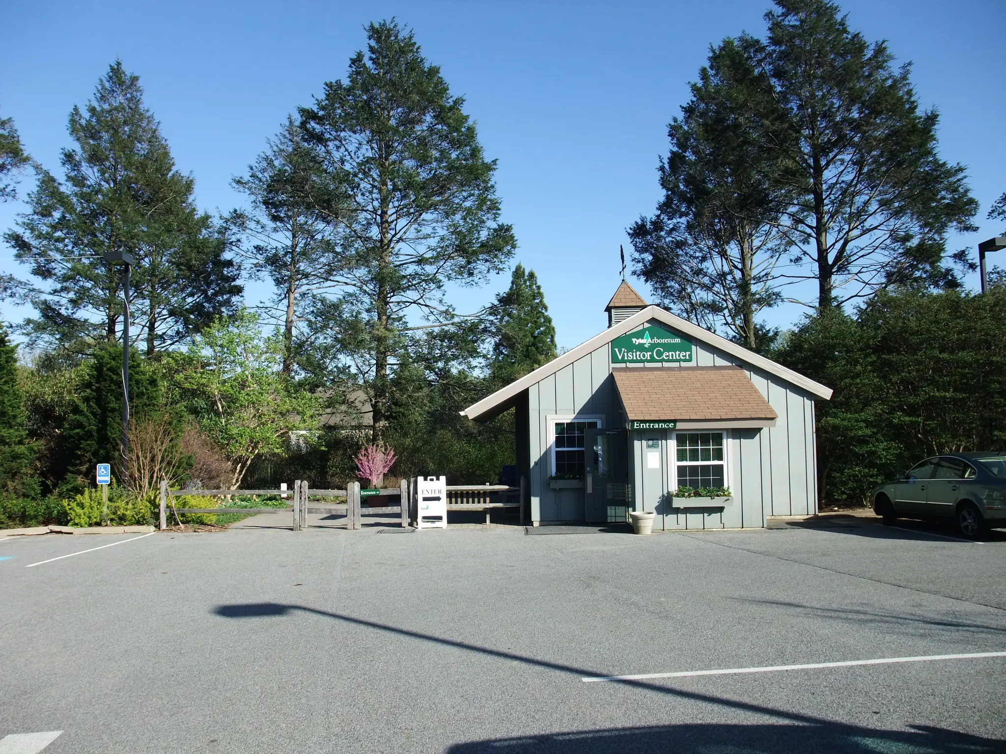 Small visitor center building next to a parking lot on a bright, sunny day.