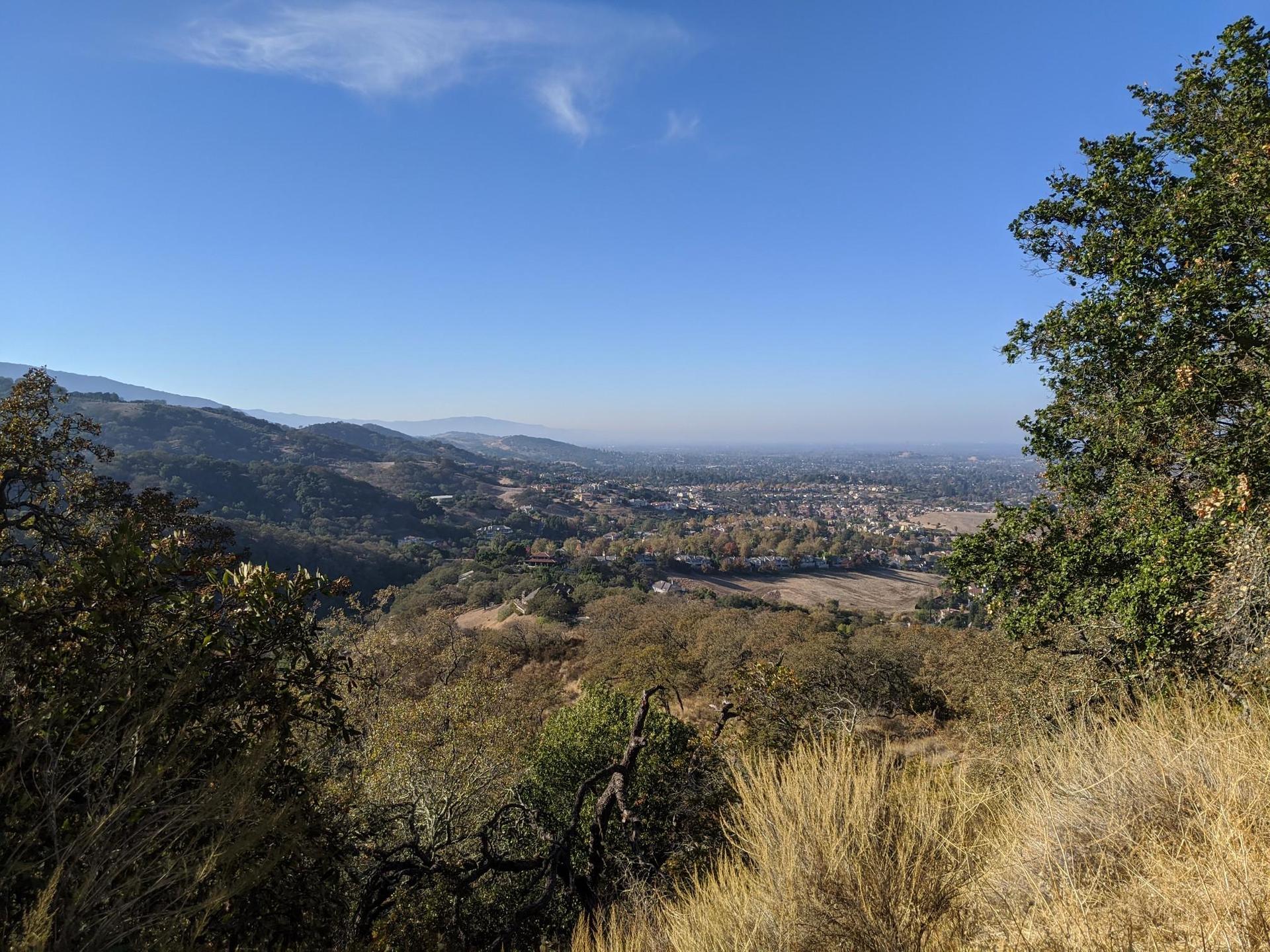 Sunny panoramic view of a valley with a distant town and hills.