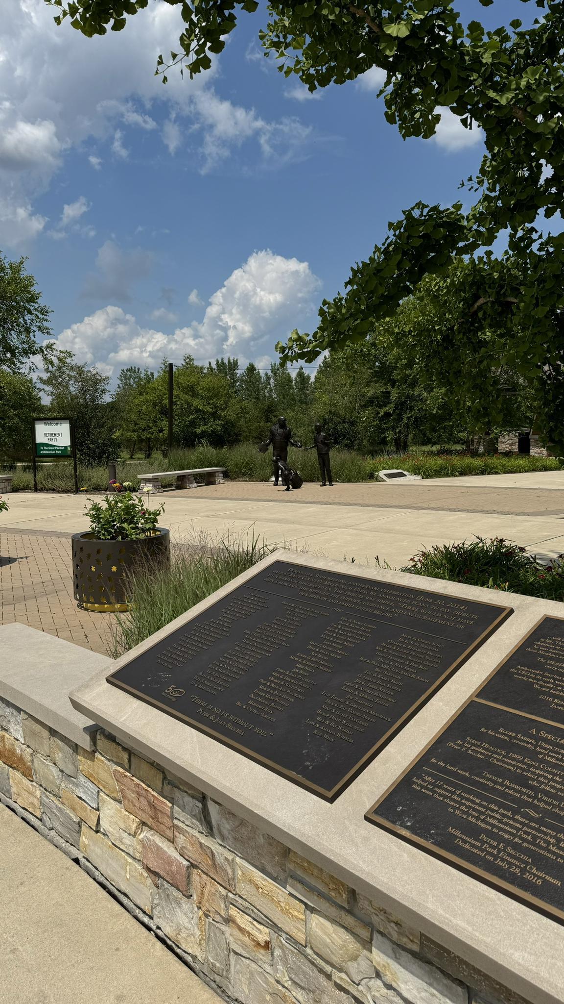 Bronze plaques on a stone wall in a sunny park with distant people.