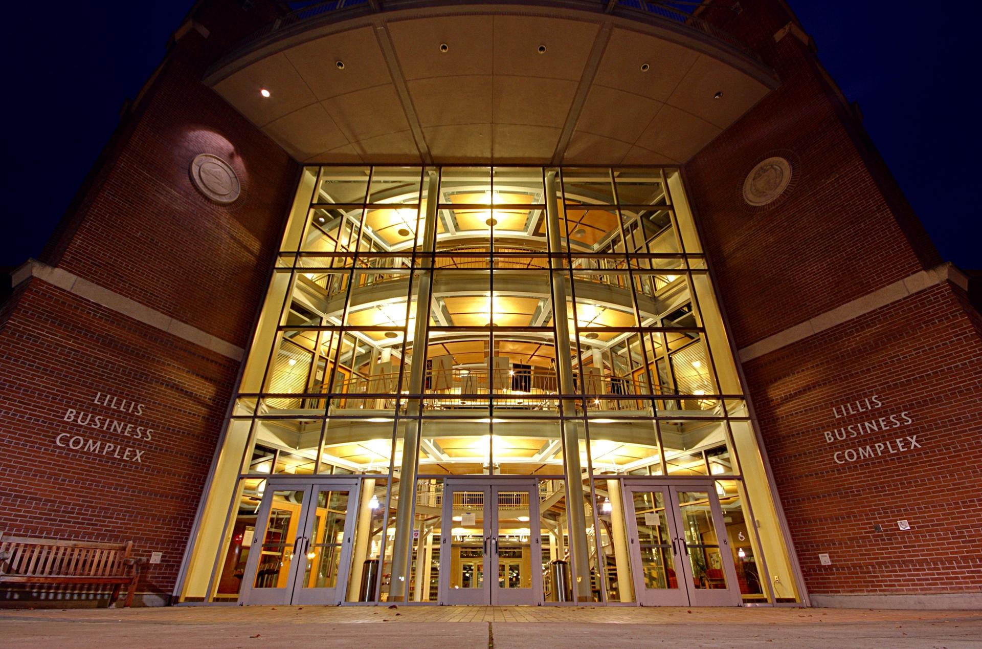 A brightly lit glass and brick building entrance at night.