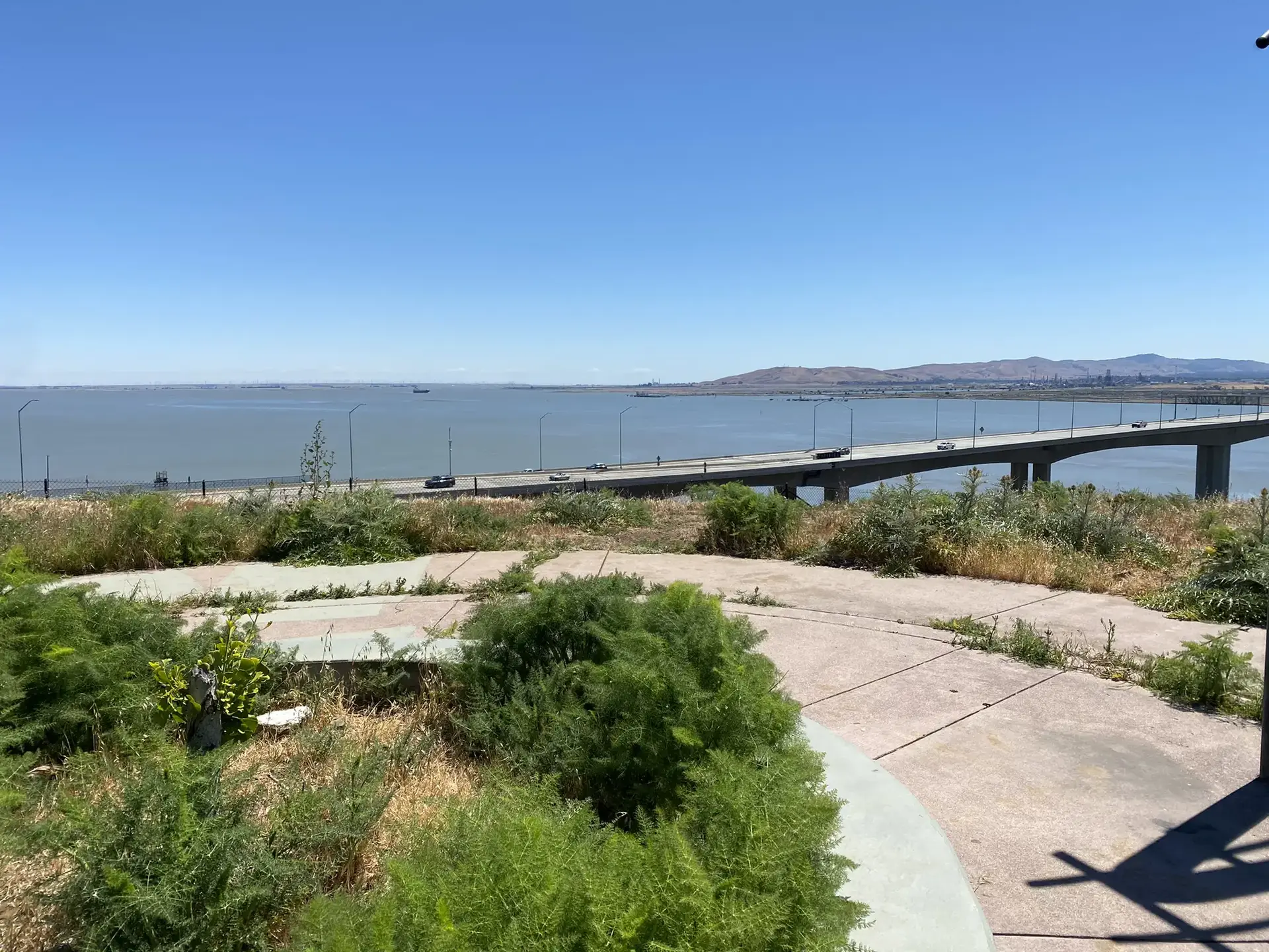Bright daylight view of a long bridge over water with cars.