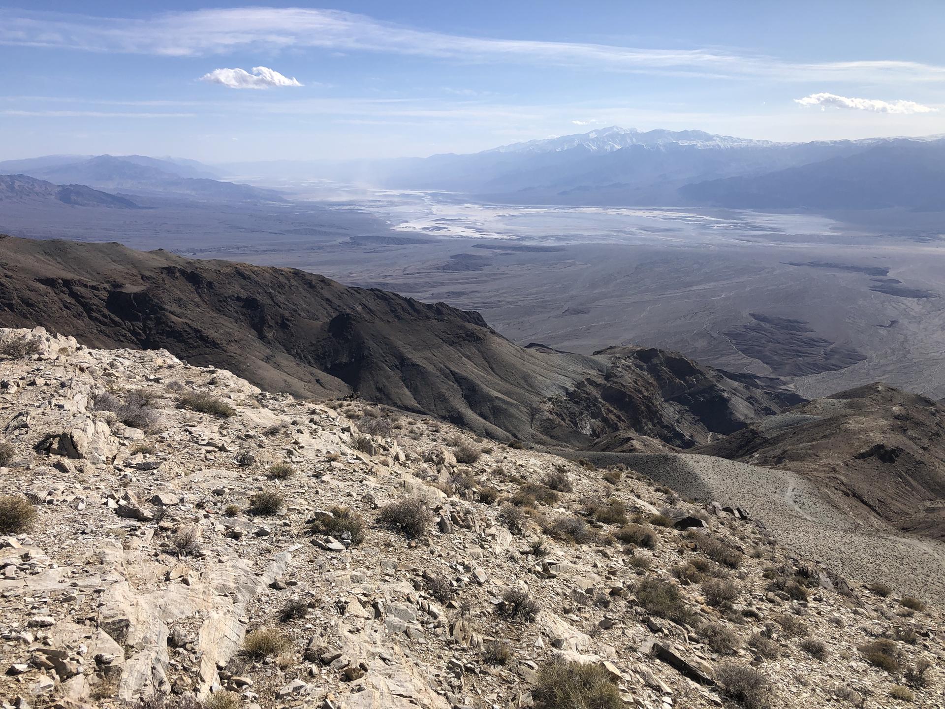 Panoramic view of a vast arid valley from a rocky mountain ridge.