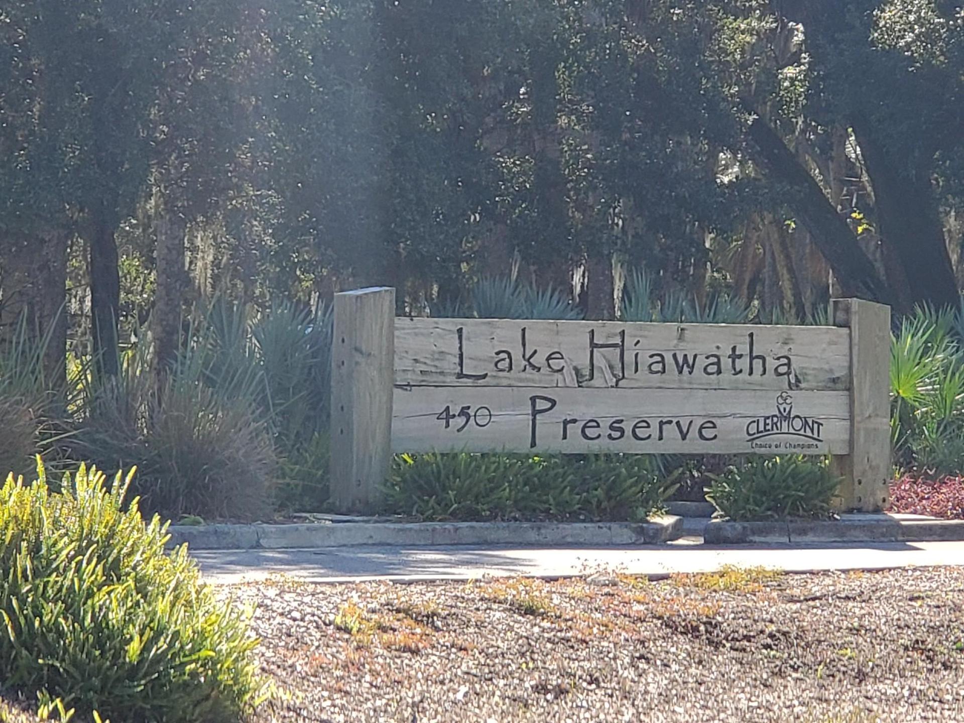 Wooden sign for a preserve, surrounded by green foliage on a sunny day.