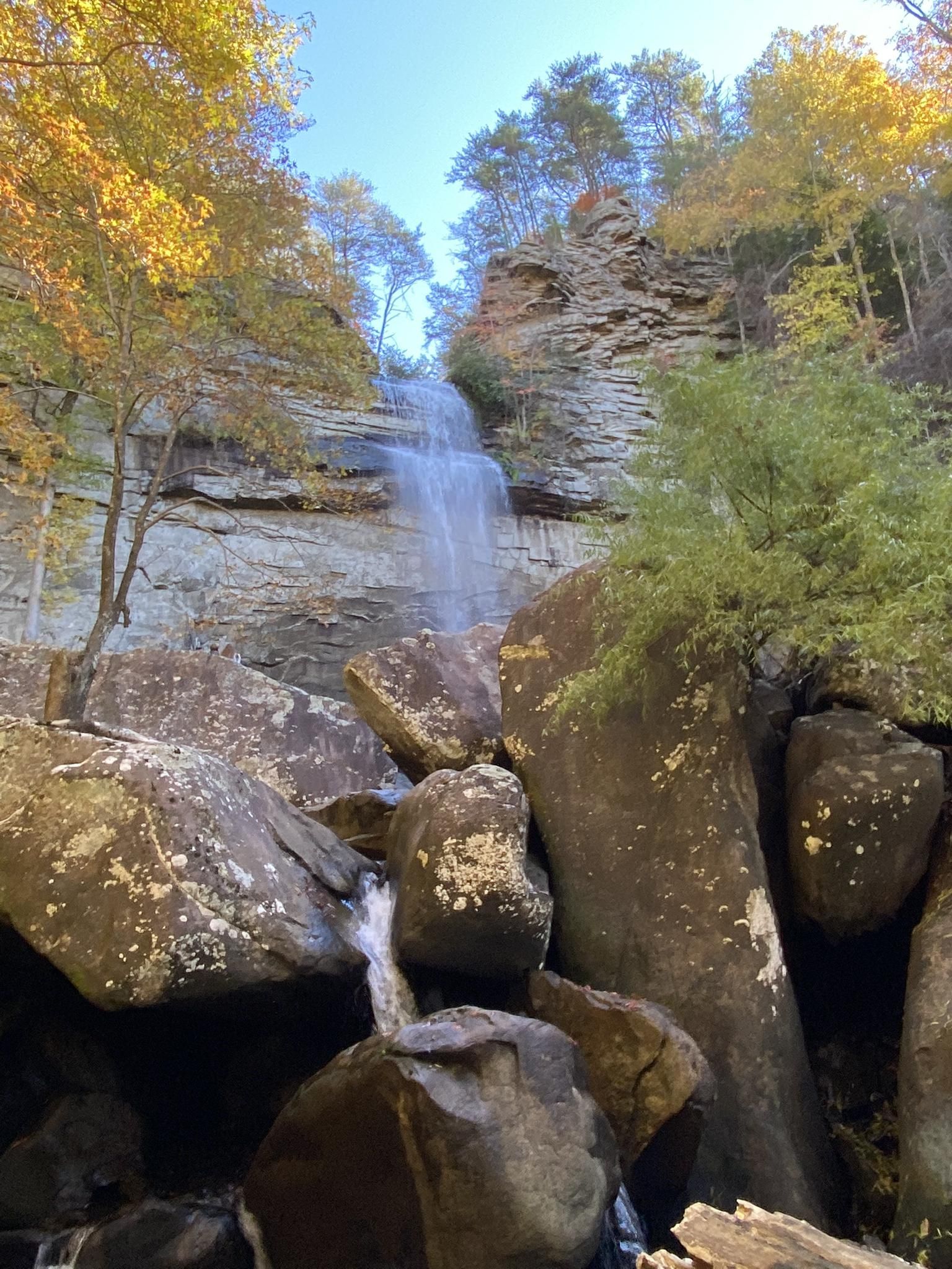 Waterfall plunges over a rocky cliff, surrounded by autumn foliage and boulders. - Laurel Falls Trail